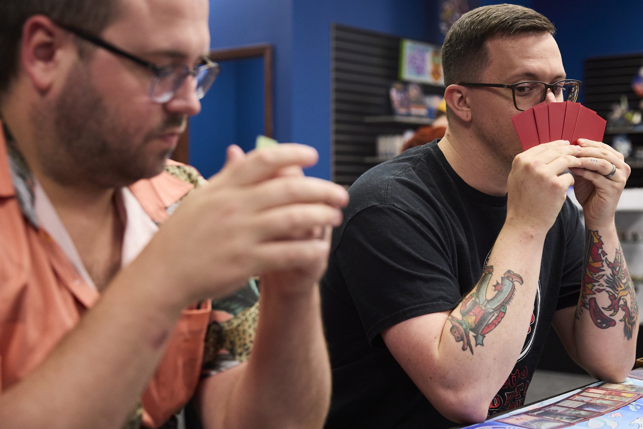 Store owner, Eric Smith, eyes Curtis Lewis' cards while he is in turn to make a move on Nov 5, 2025, at Deep Dive Card Shop in Athens, Ohio. “With being the new blood, it was very important for us to be different than the other stores. We had the peo