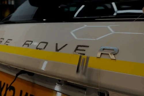 Range Rover lettering being lined up on a white tailgate with tape
