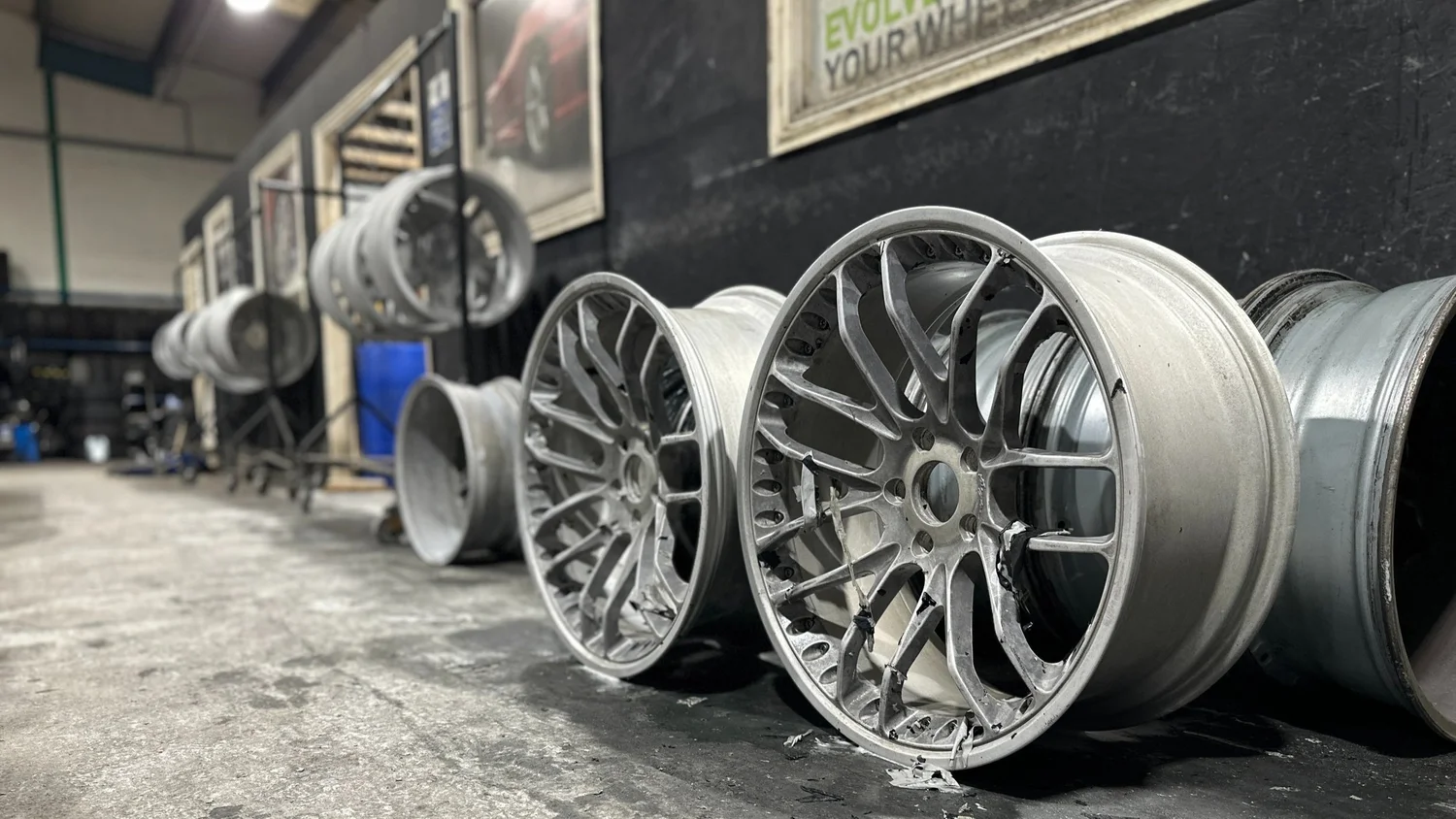 Stripped alloy wheels lined up on the workshop floor ready for refurbishment
