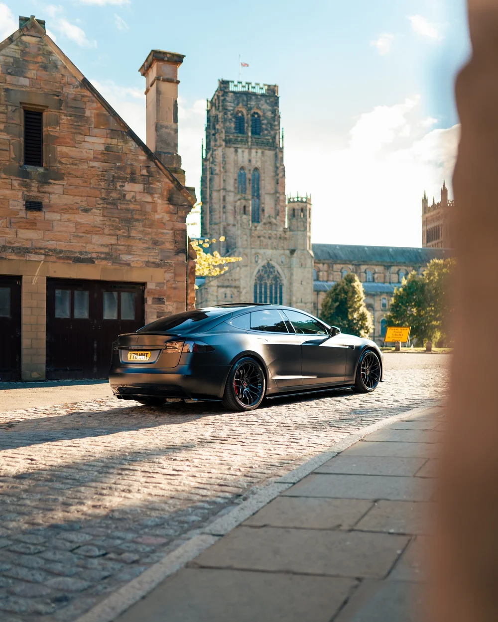 Satin black wrapped Tesla Model S parked on a cobbled street