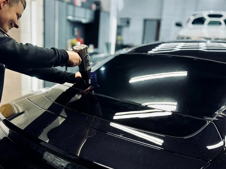Technician fitting tint to a black Porsche at TintTech Nottingham