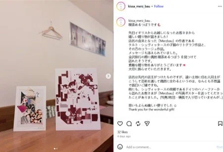 Photo of three art pieces or posters on a wooden surface, with a wall and a coat hanger in the background. The largest poster features a pixelated or abstract design. The other two artworks are smaller, one with a character illustration.