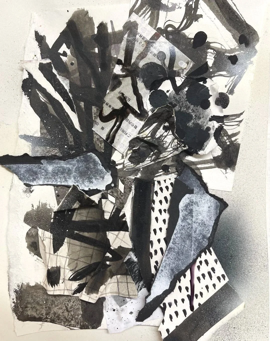 Collage of torn black and white papers with abstract shapes, textures, and patterns, including Chinese text and a partially visible banknote.
