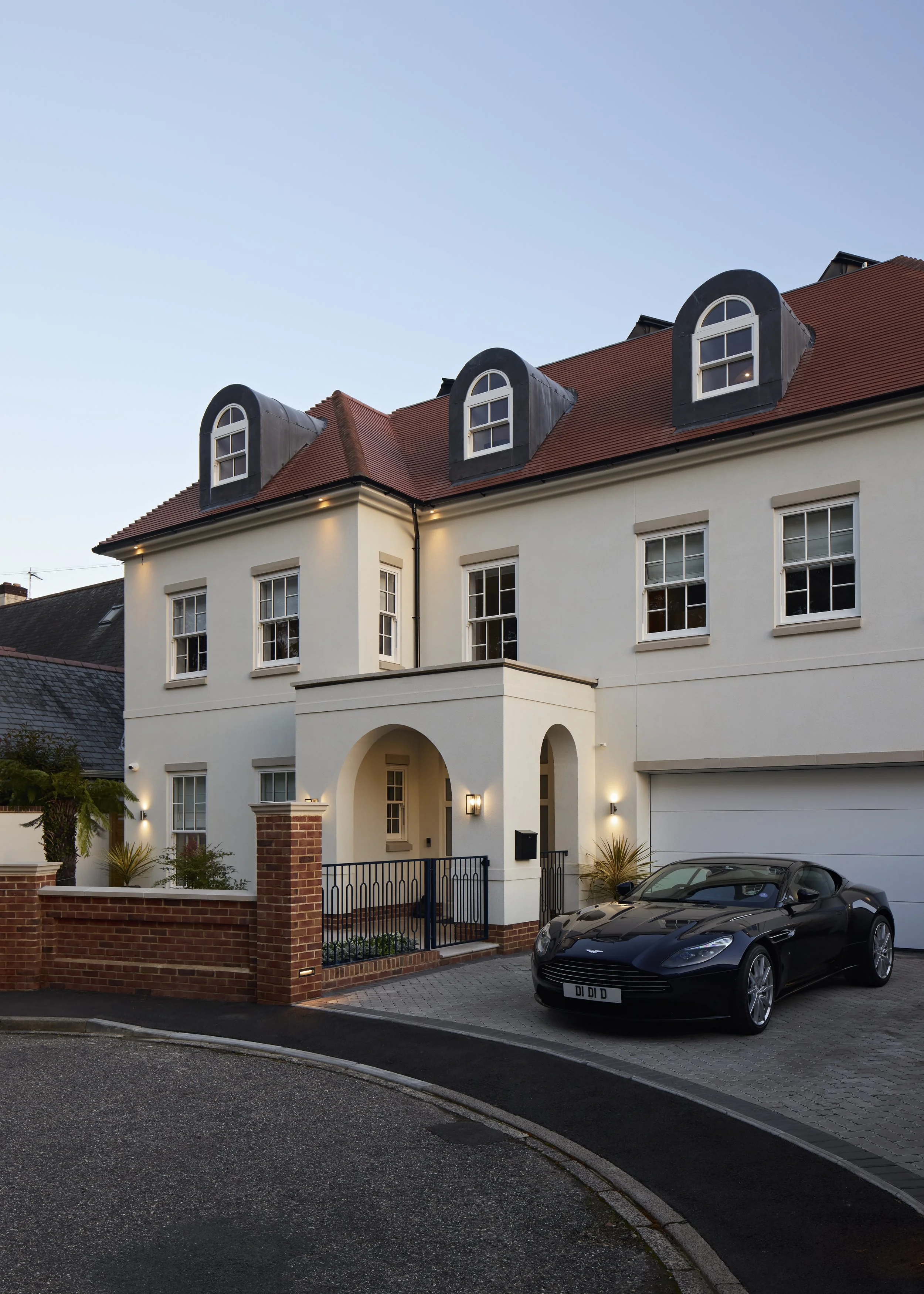 Front elevation of the Over Links home at dusk with dormer roof and arched entrance
