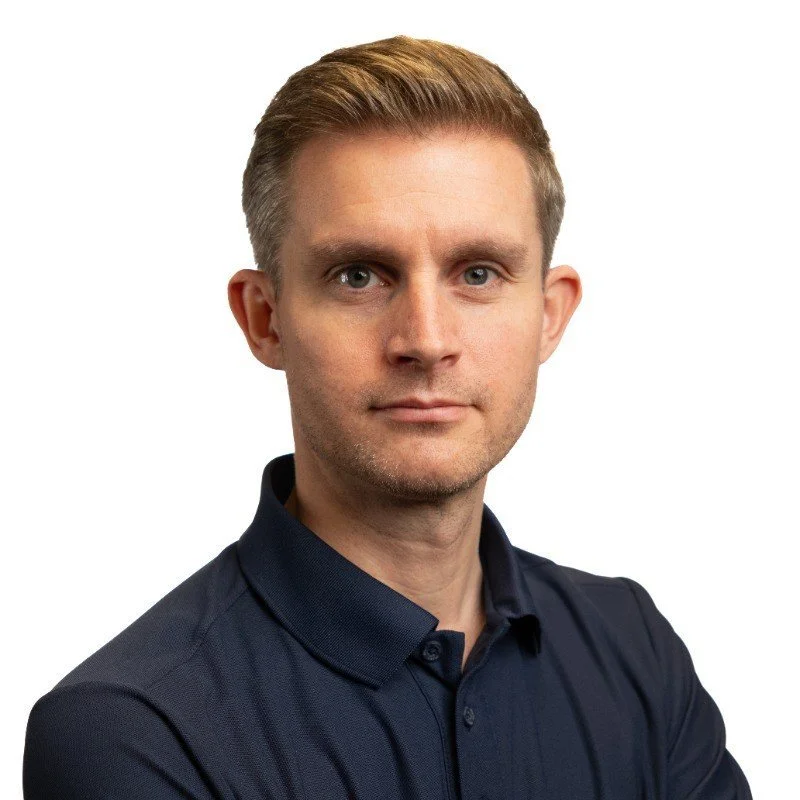 Portræt af en mand med kort hår og mørk skjorte.