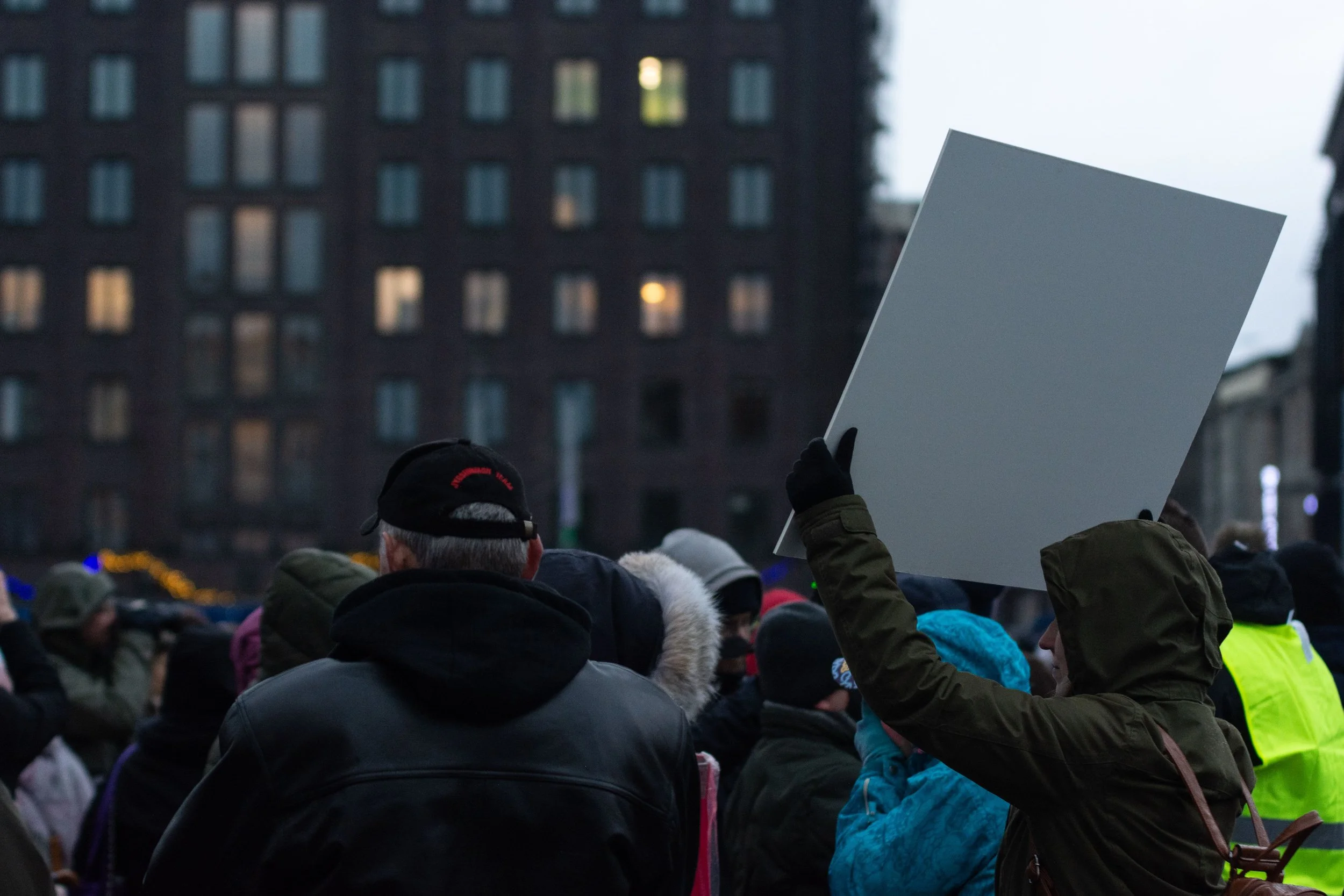 People rallying outside a building on an evening in the winter.
