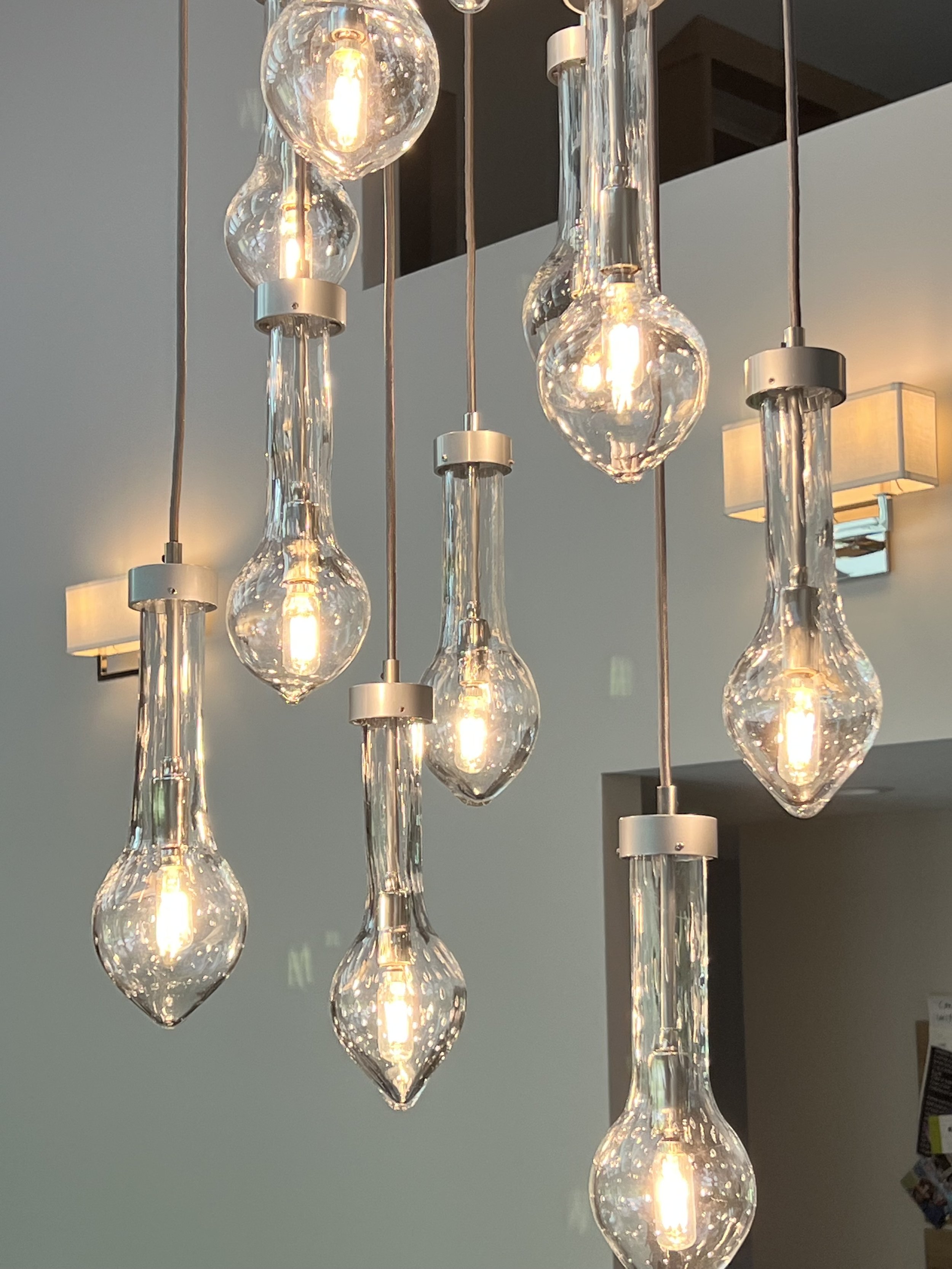 Multiple hanging glass pendant lights with illuminated bulbs in a modern interior.