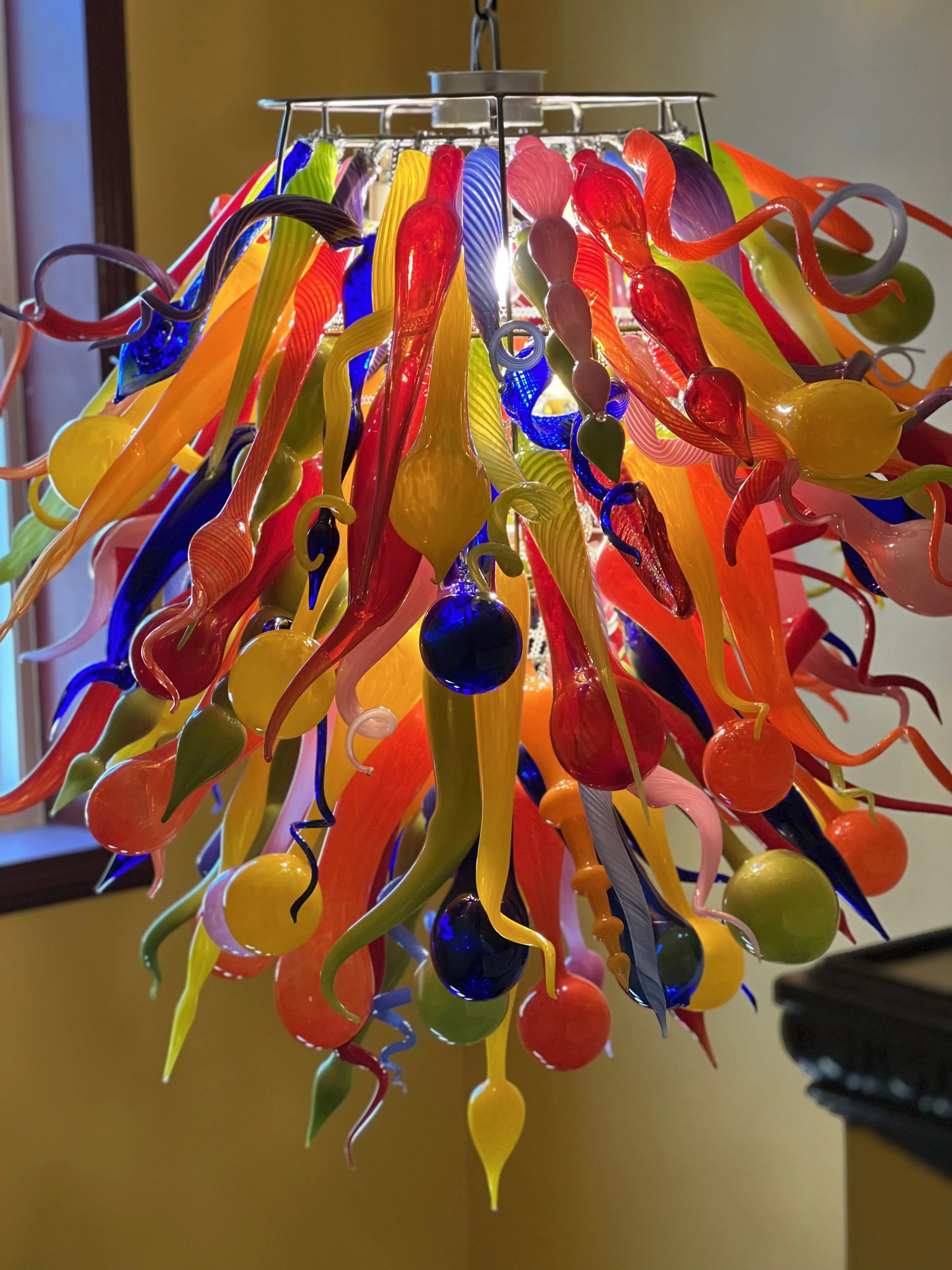 Colorful blown glass chandelier with various twisted and curved glass pieces hanging from a metal frame.