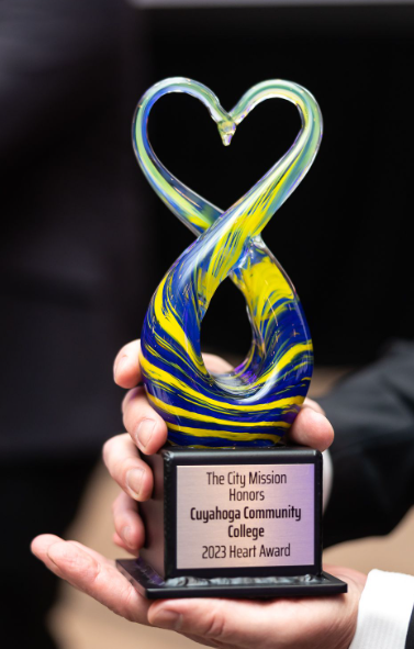 Colorful glass heart sculpture on a black base with an inscription for Cuyahoga Community College's 2023 Heart Award.