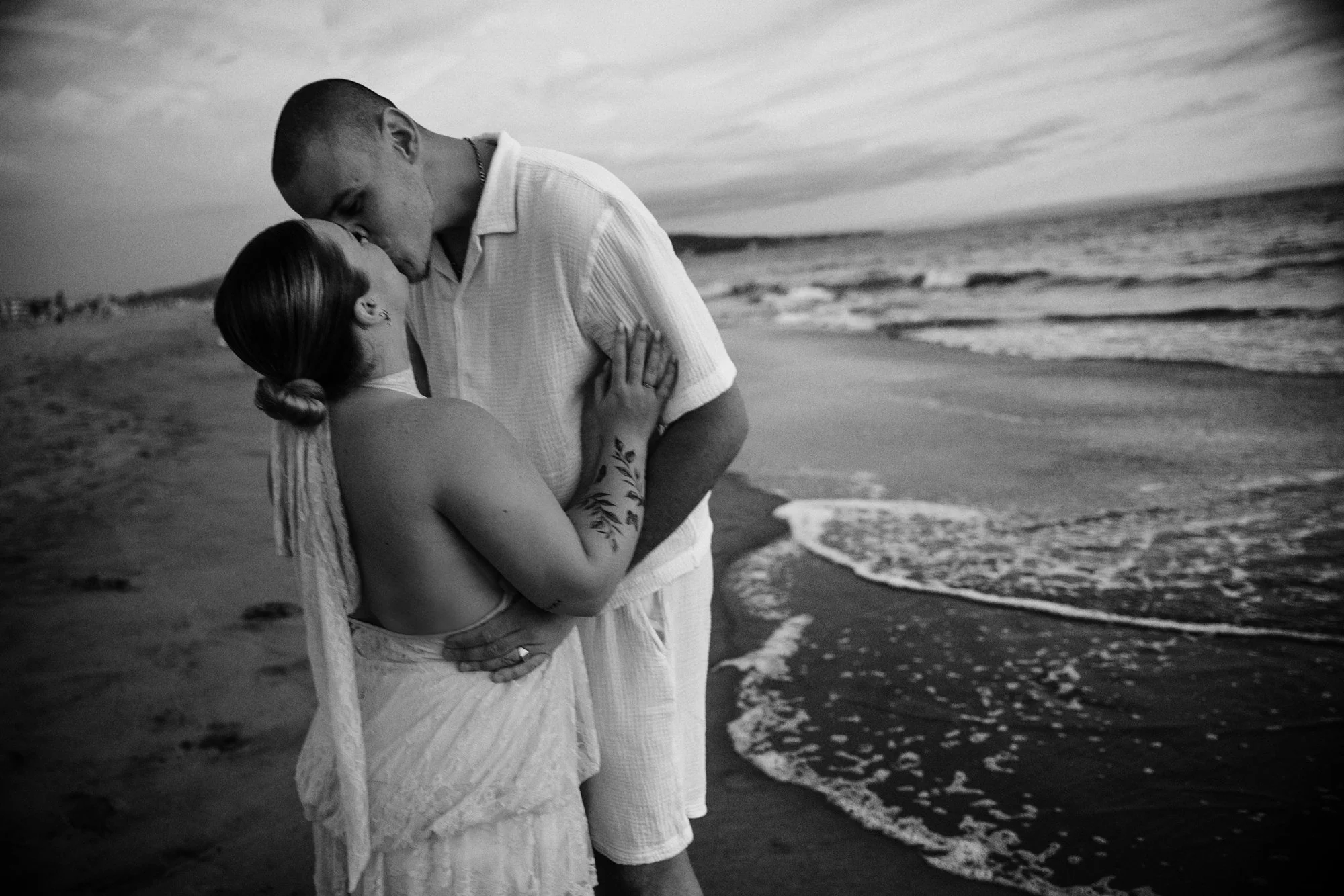 Maëlle and Djamel kiss after their sunset surprise proposal on the beach in Manhattan Beach, California.