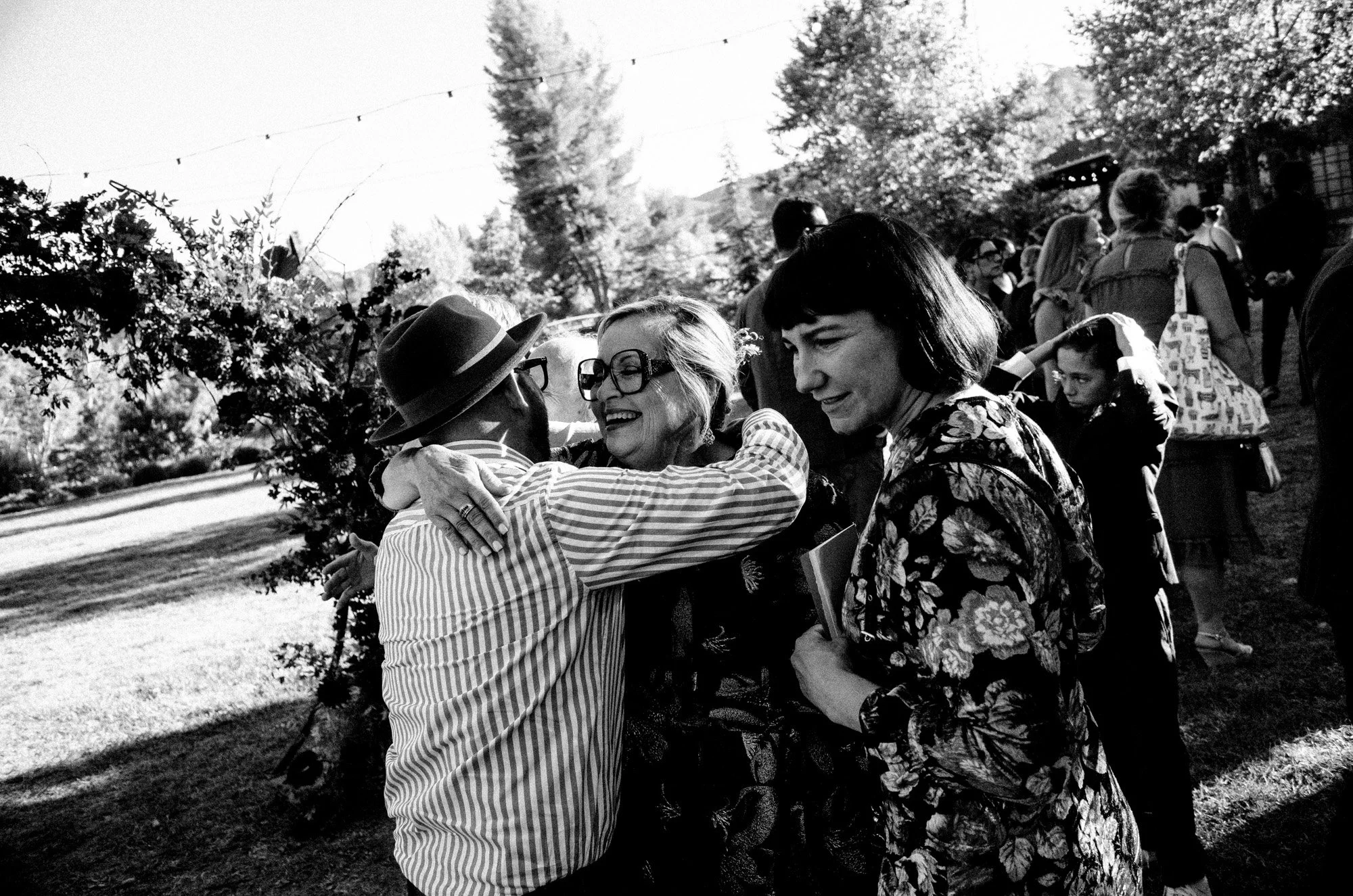 Wedding guests greeting one another with an embrace outdoors.