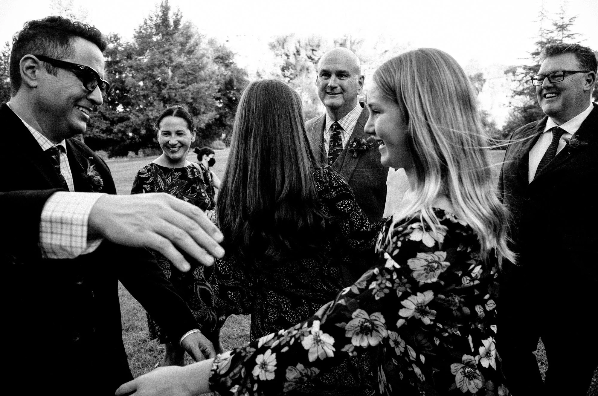 Guests smiling together during an outdoor wedding celebration.