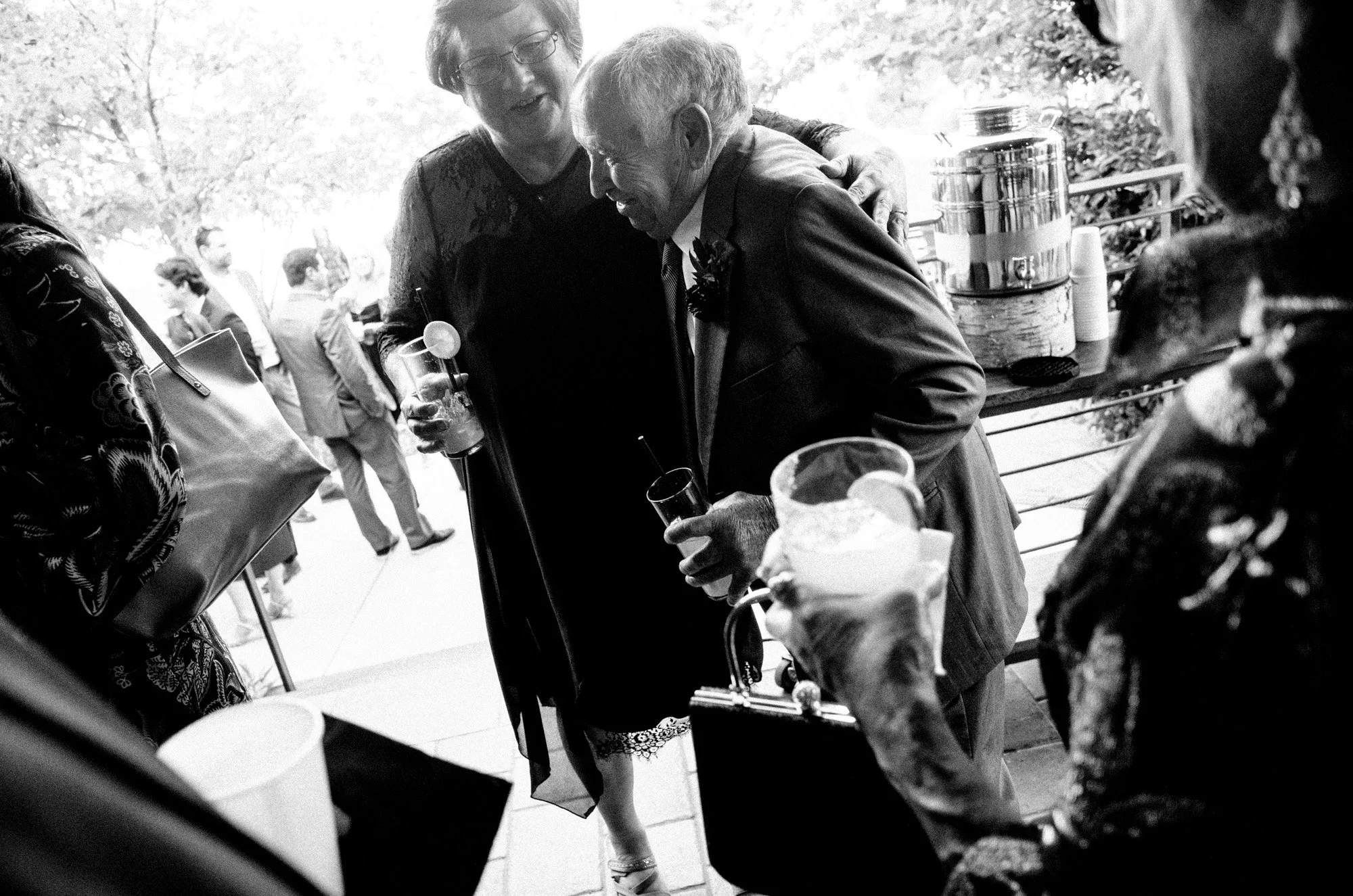Wedding guest leaning forward with a drink during the reception.