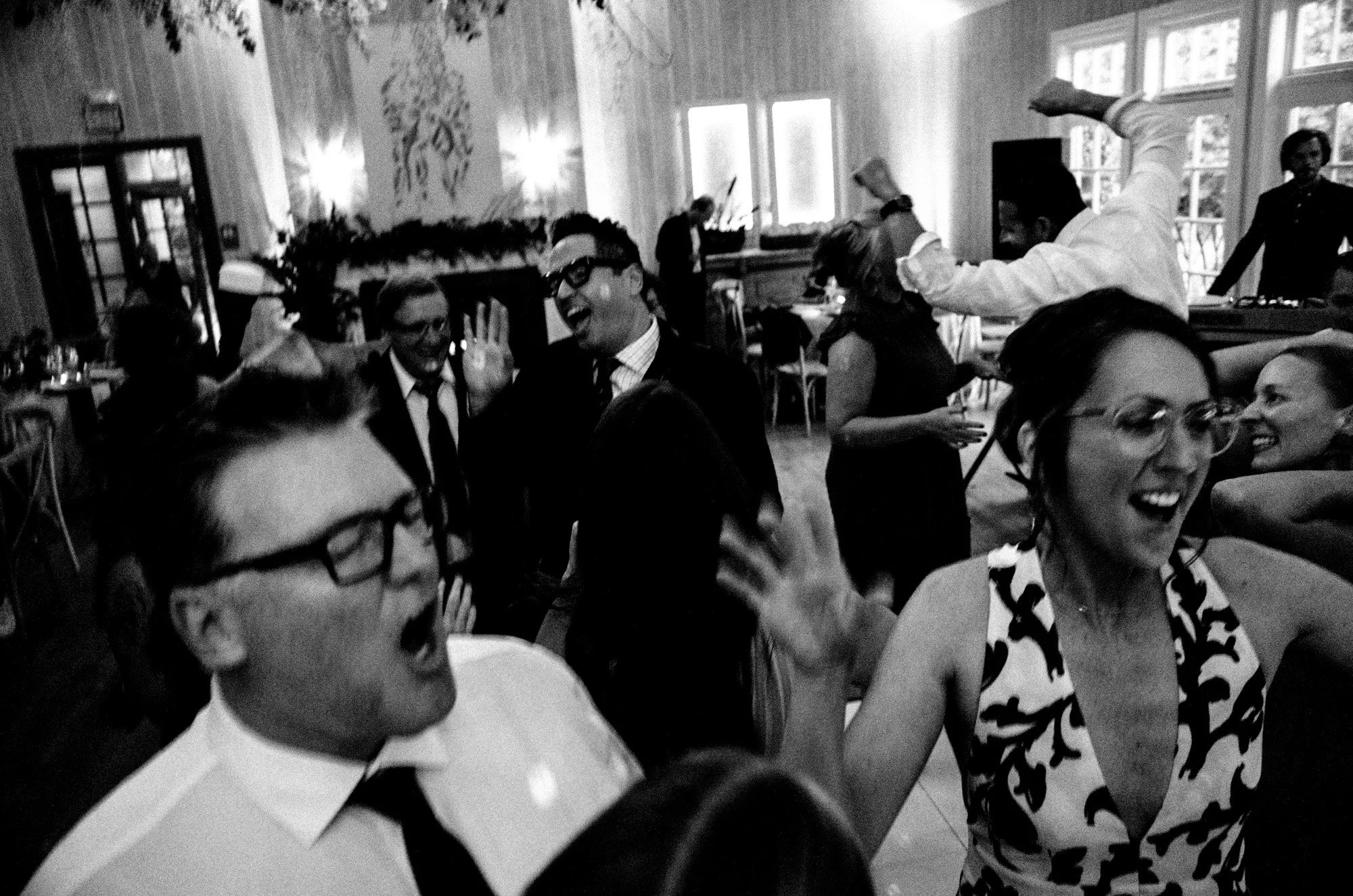 Wedding guests dancing and laughing during the reception.