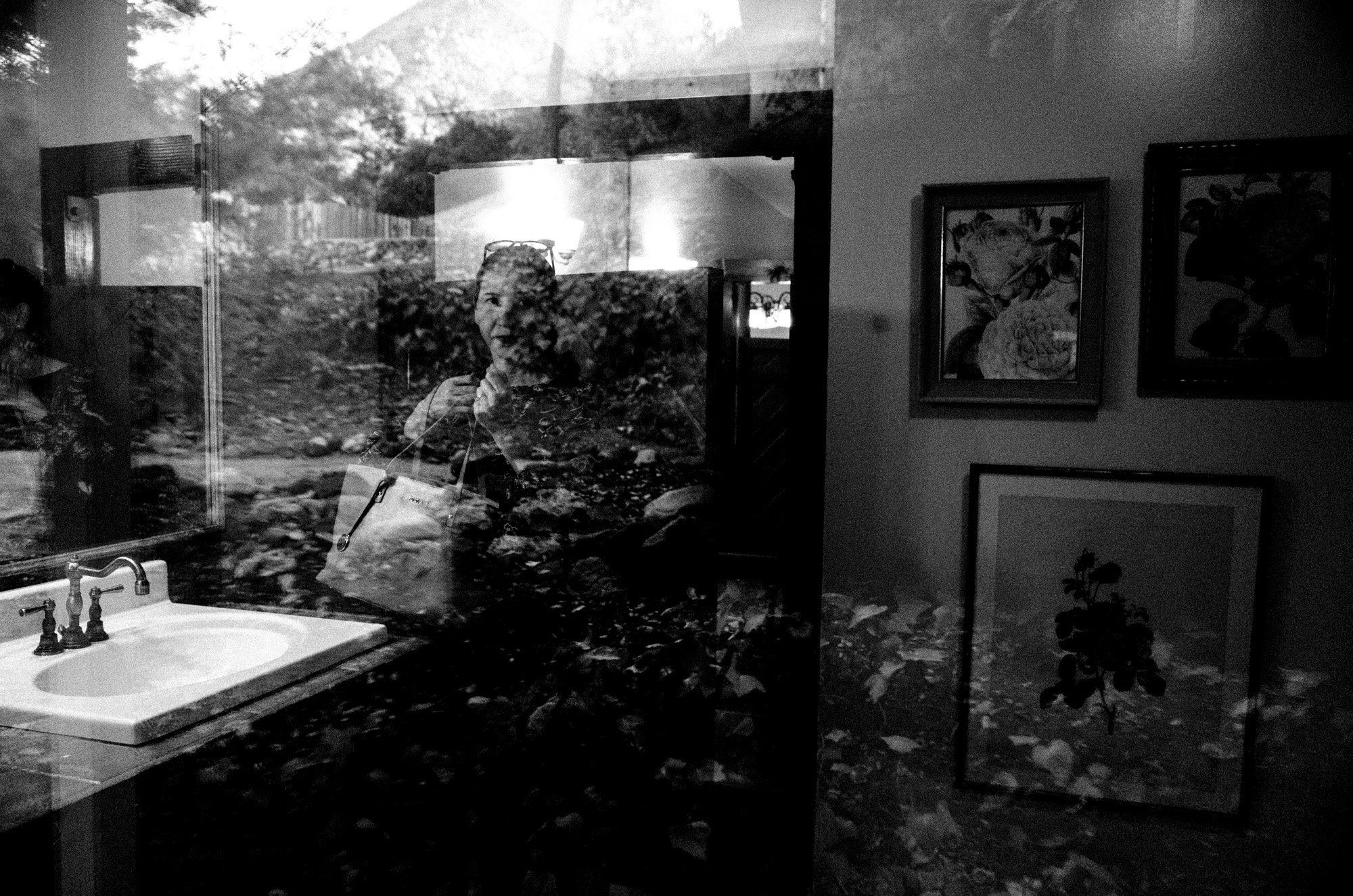 Wedding guest seen through layered window reflections inside the venue.
