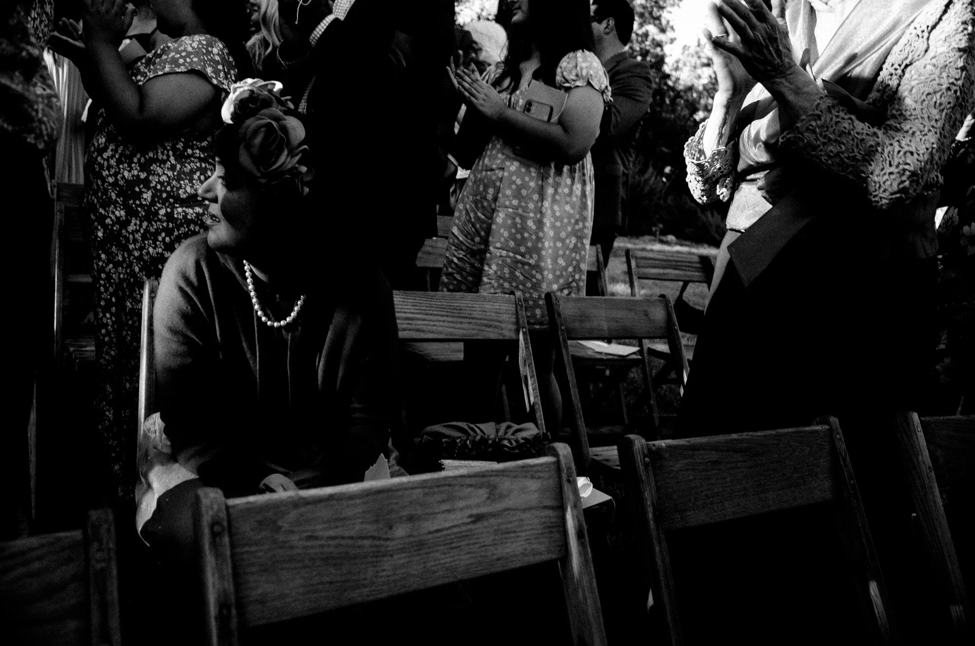Wedding guests sharing a candid exchange from their ceremony chairs.