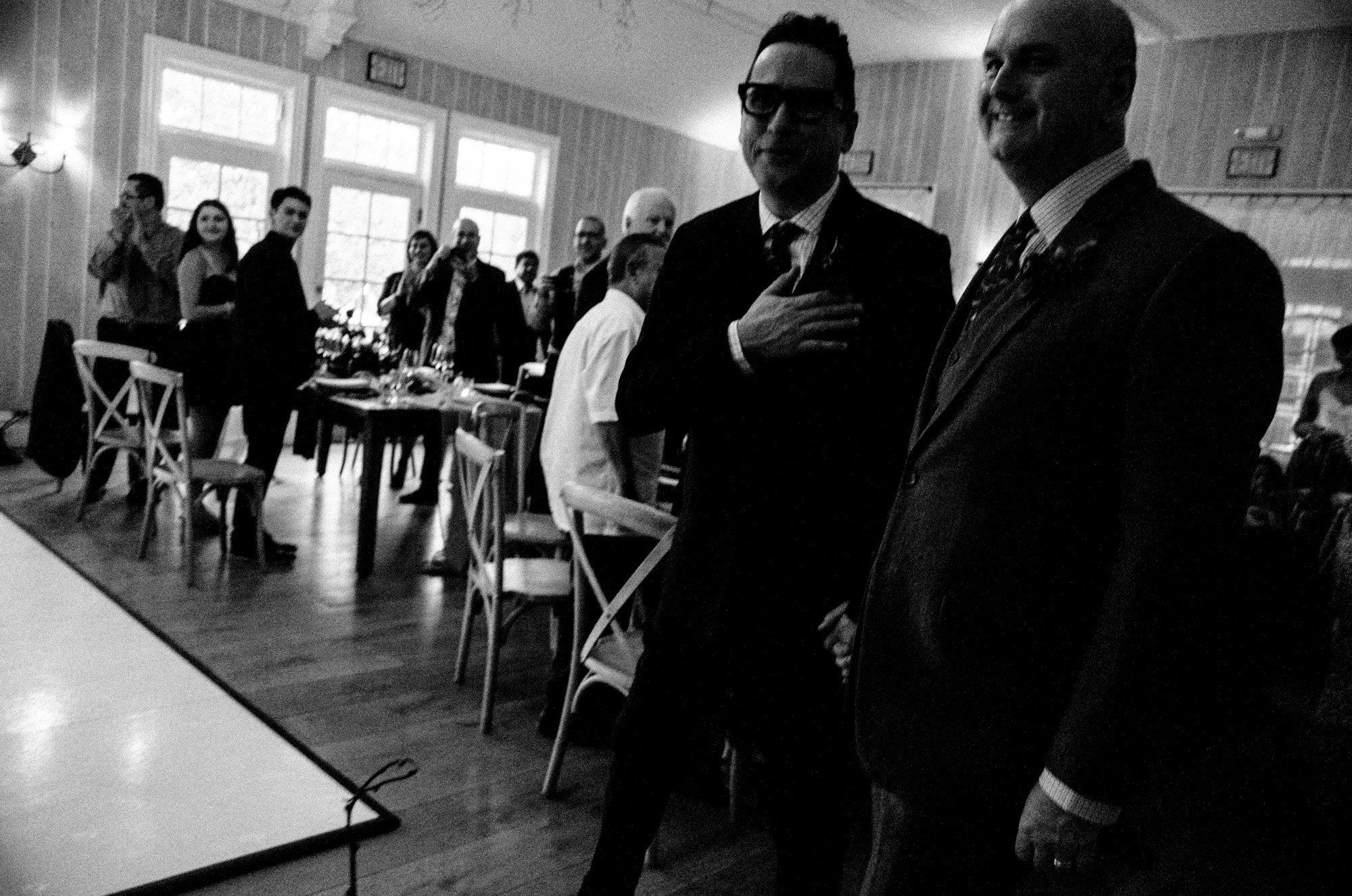 Two grooms standing together during an indoor reception.