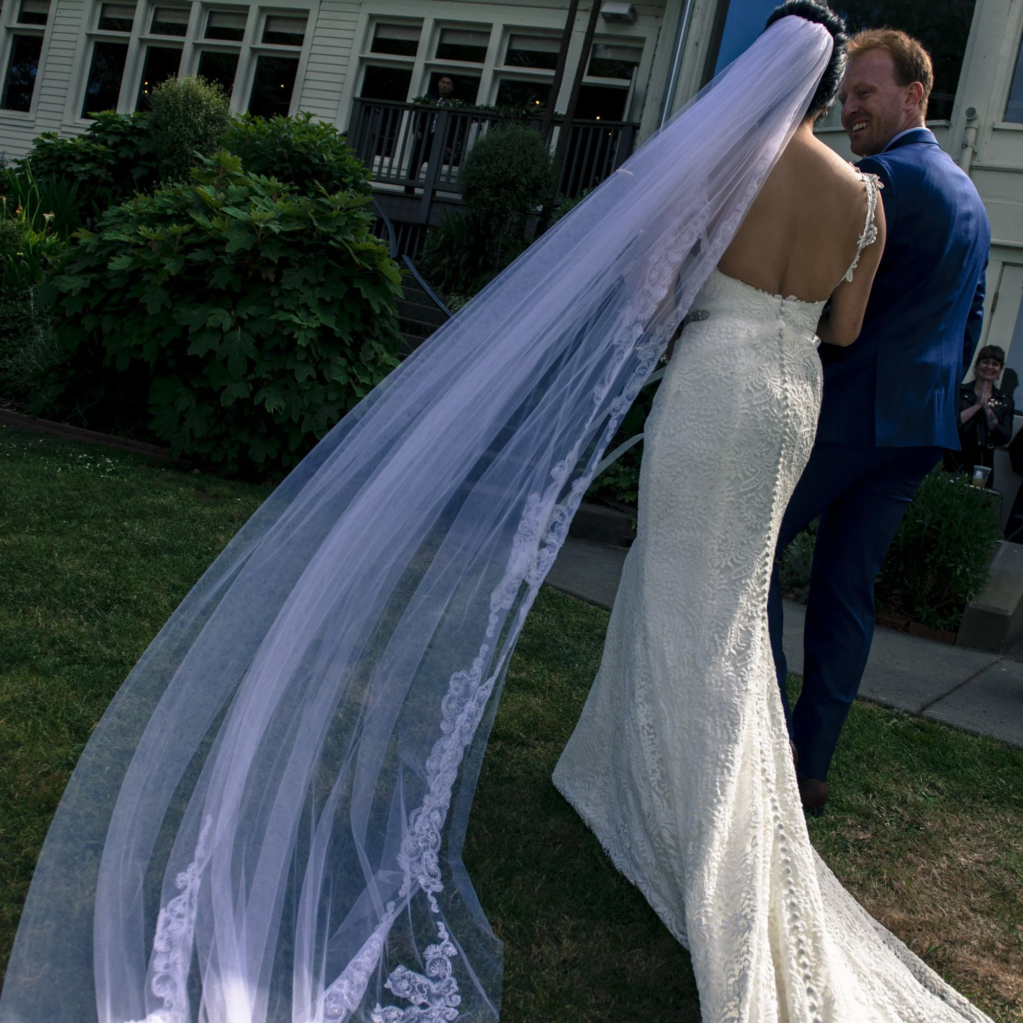 Newlyweds kissing outdoors beneath the bride’s flowing veil.