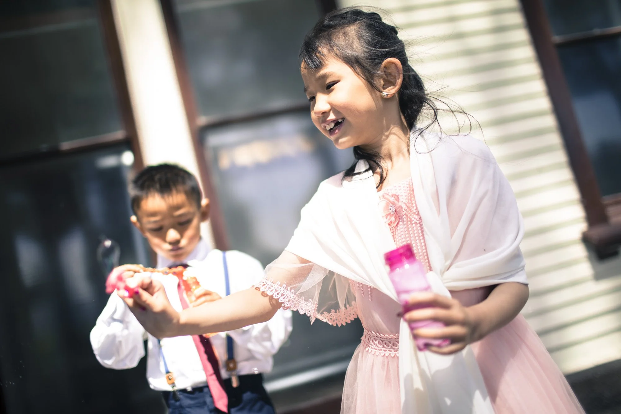 Smiling child blowing bubbles during wedding preparations.