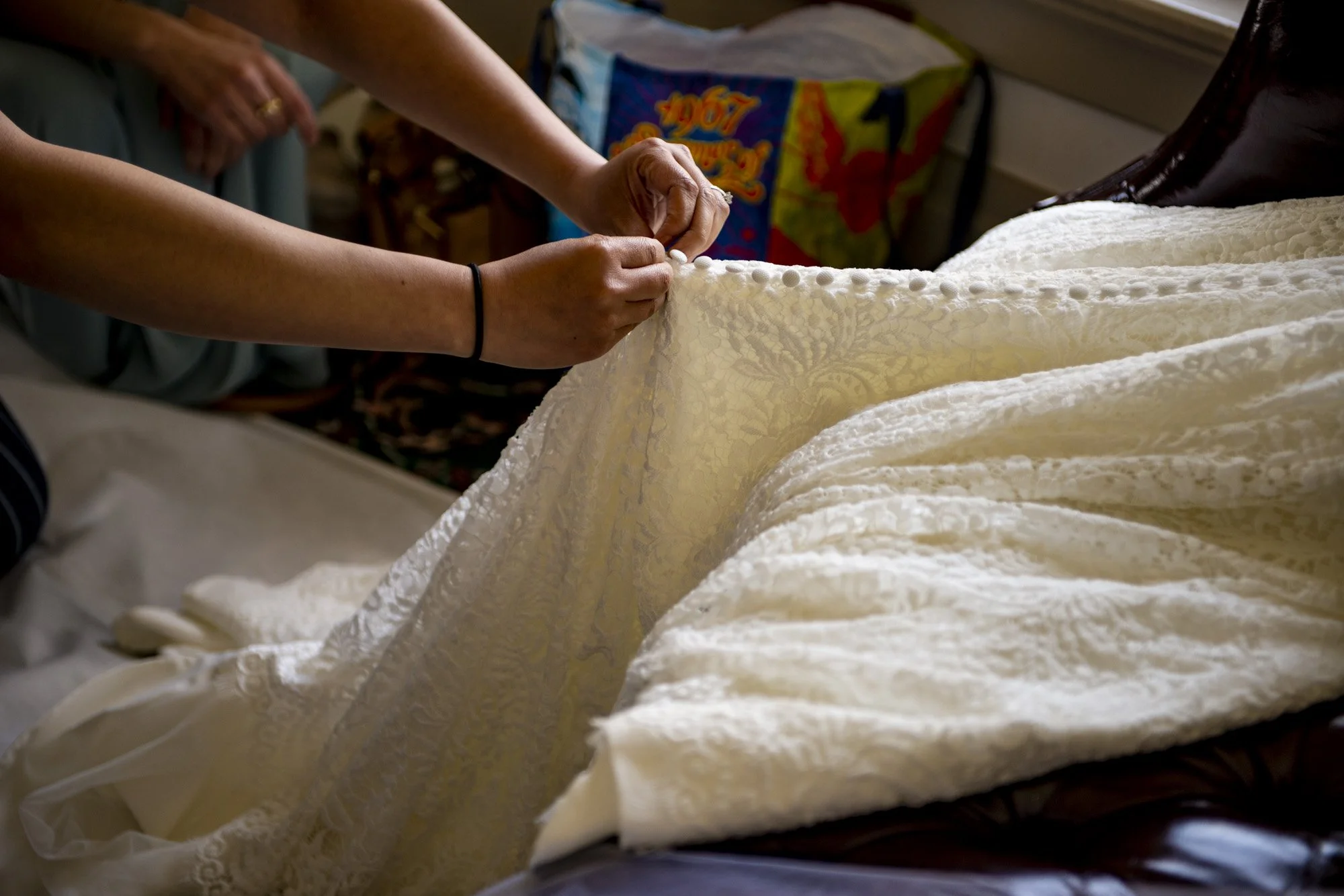 Hands arranging the fabric of a wedding dress during preparations.