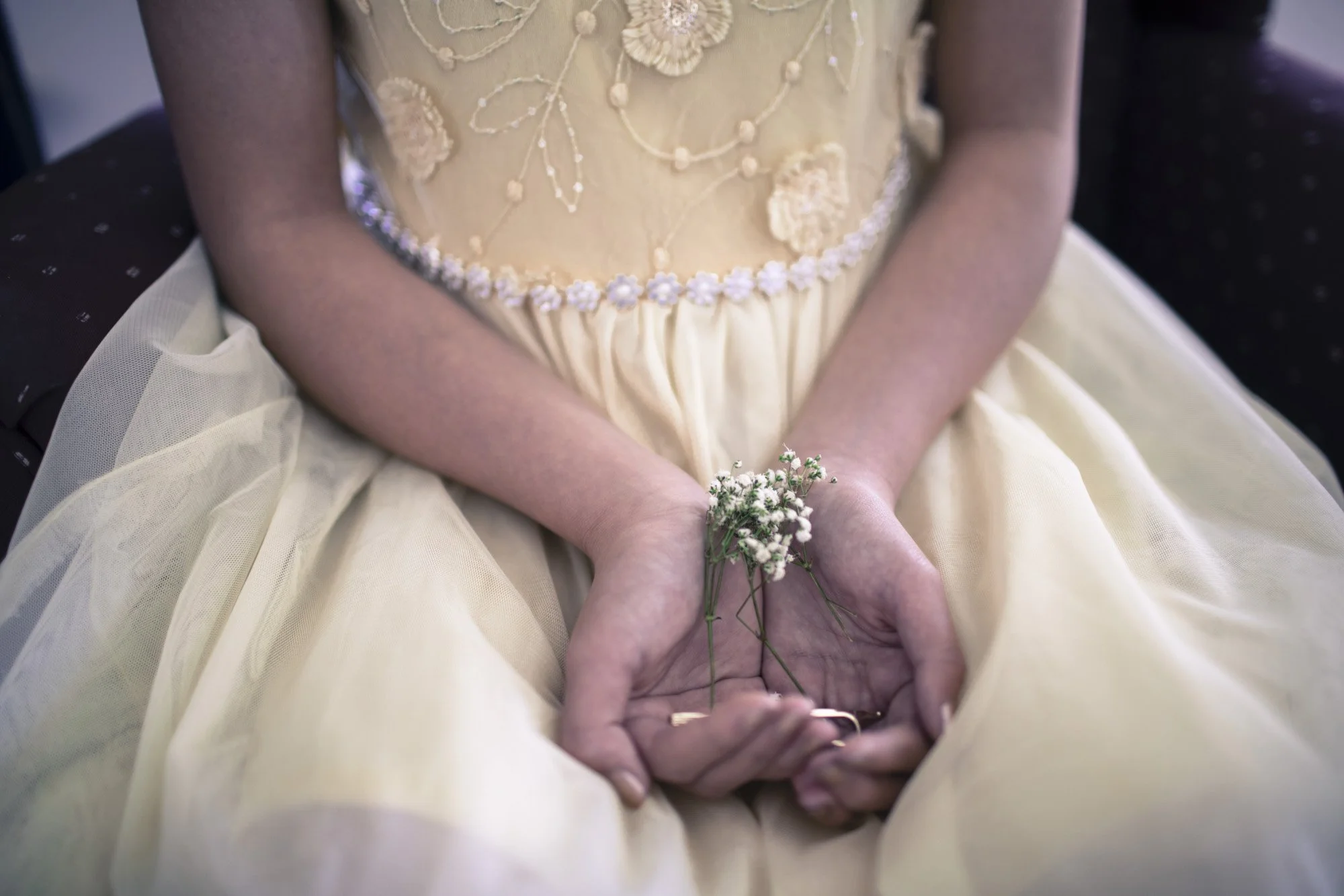Flower girl holding a small bouquet in her lap.
