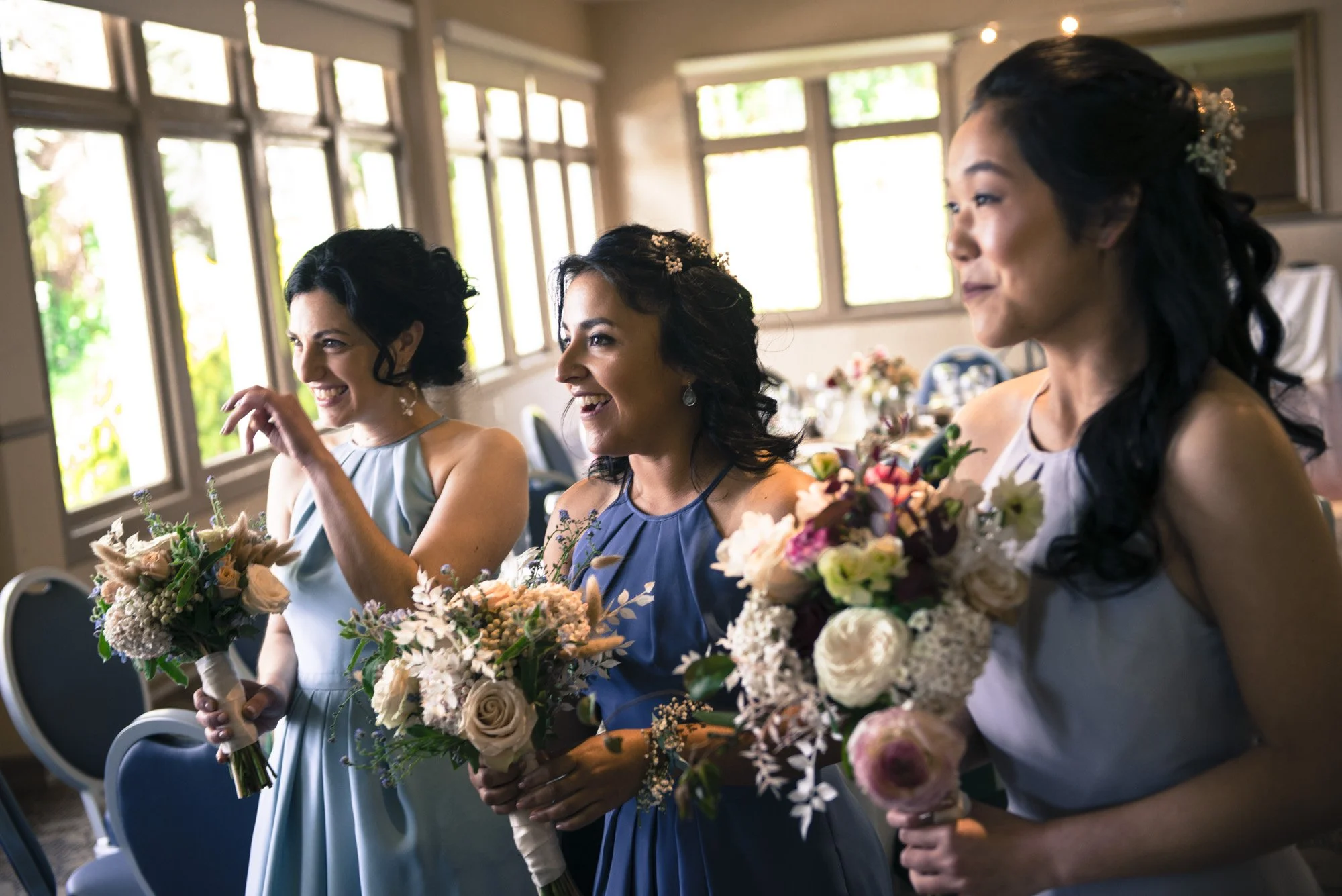 Bride and bridesmaids smiling together while holding their bouquets.