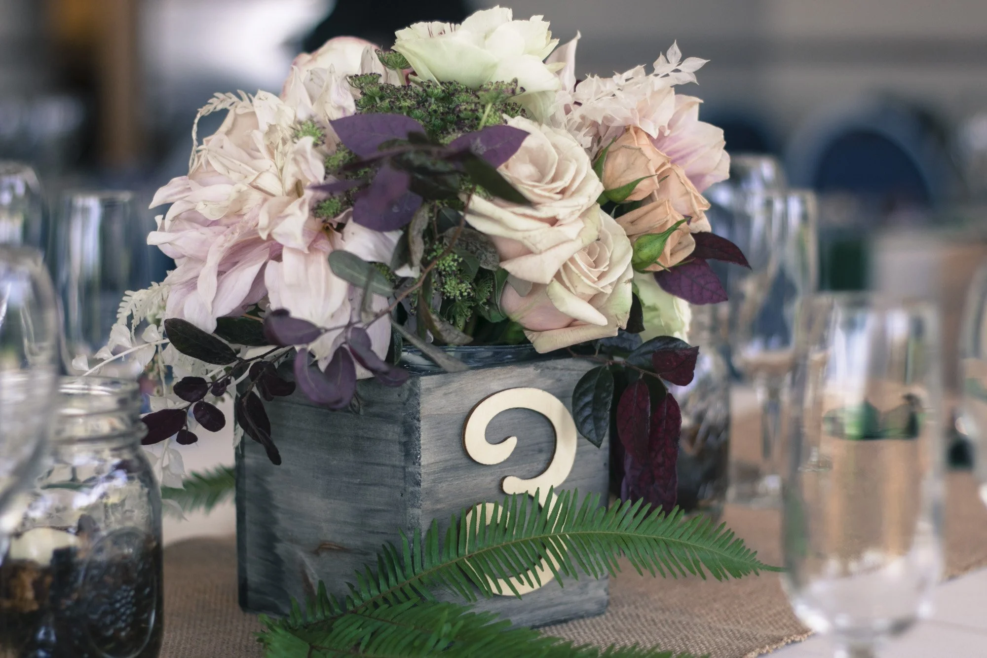 Floral wedding centerpiece arranged around table number three.