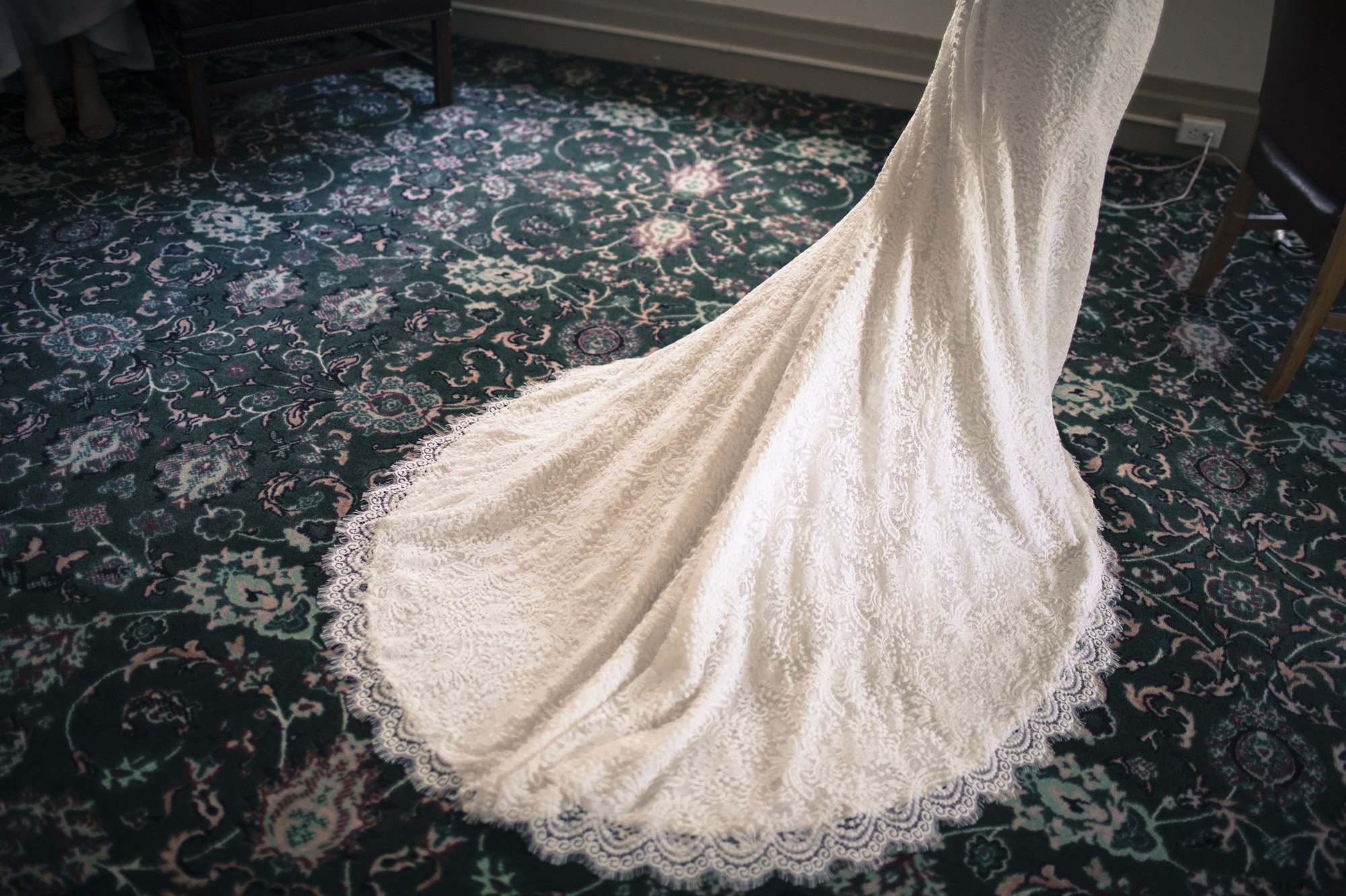 Wedding dress train spread across a patterned carpet.