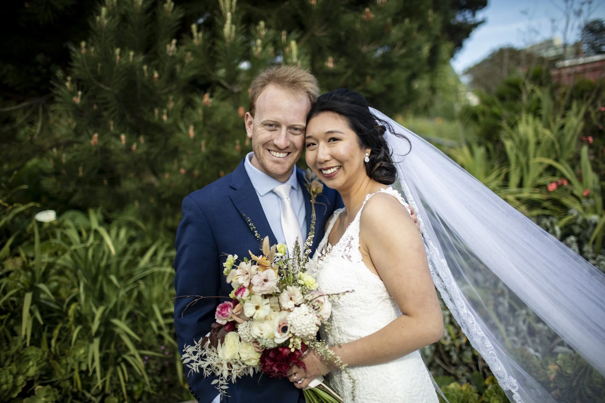 Newlyweds smiling closely together with the bride’s veil drifting behind them.