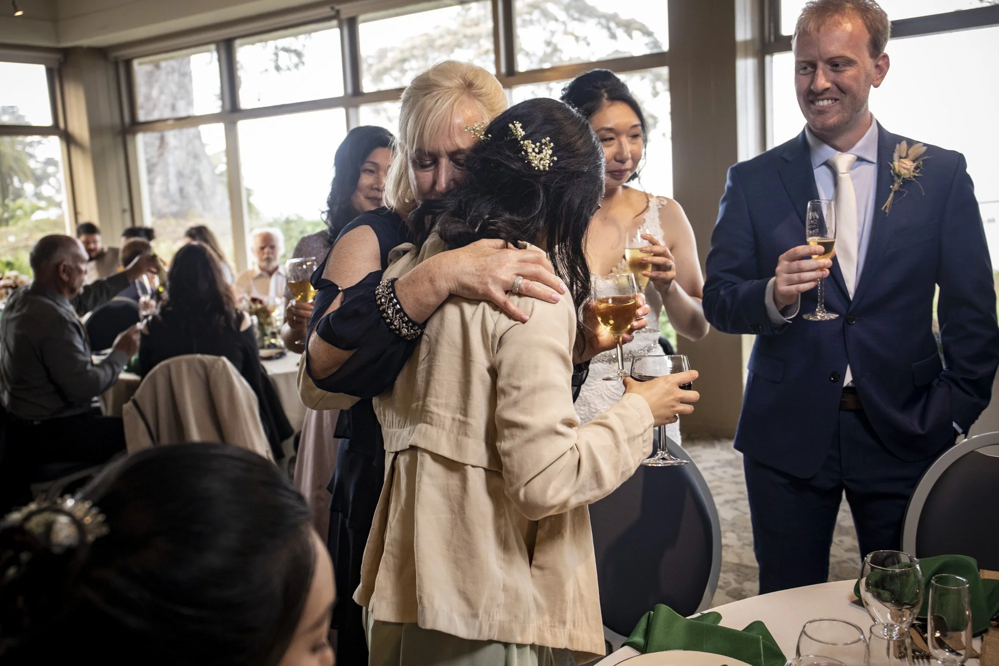 Wedding guest holding someone close during an emotional reception moment.