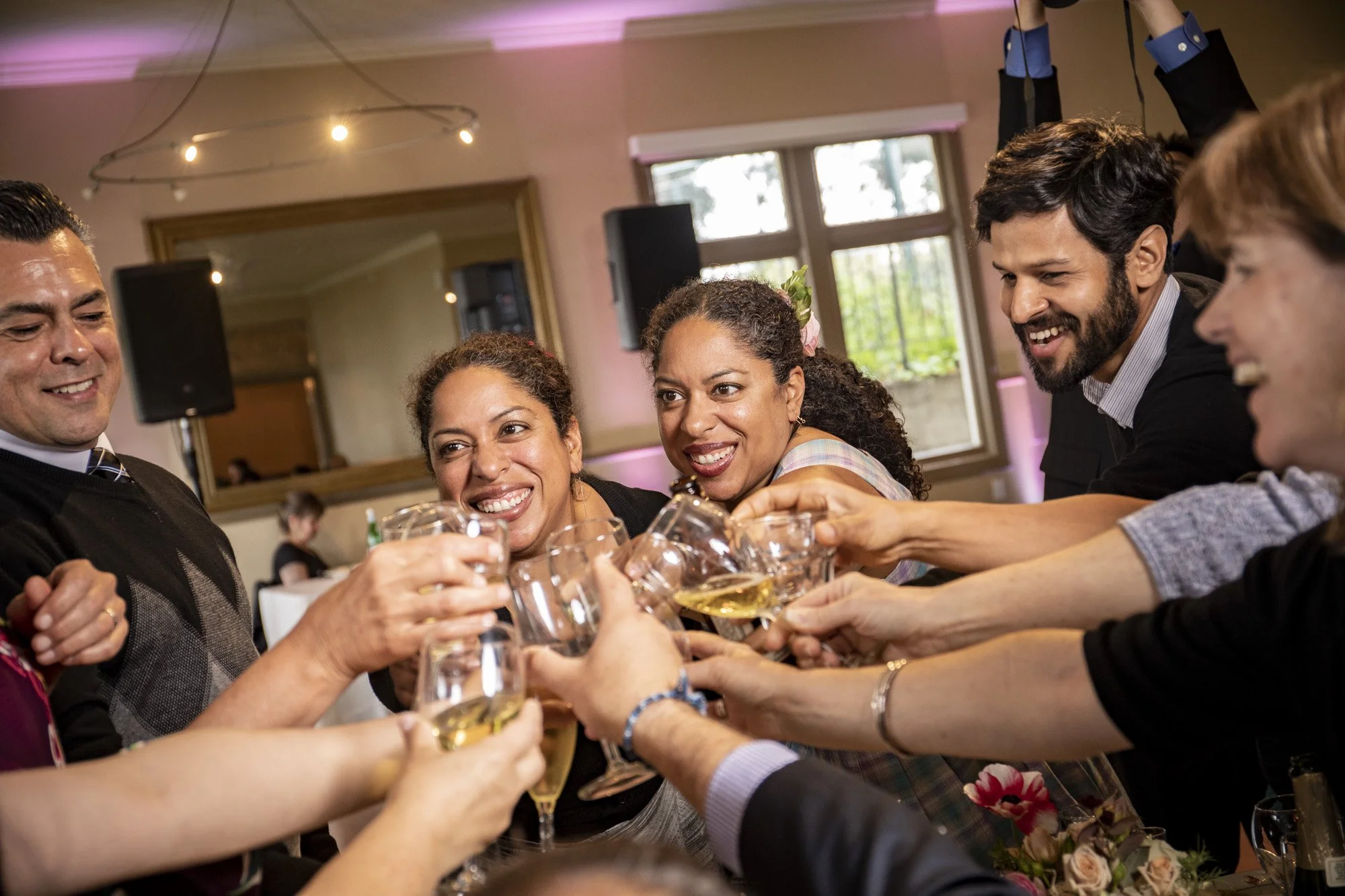 Wedding guests leaning together for an energetic group toast.