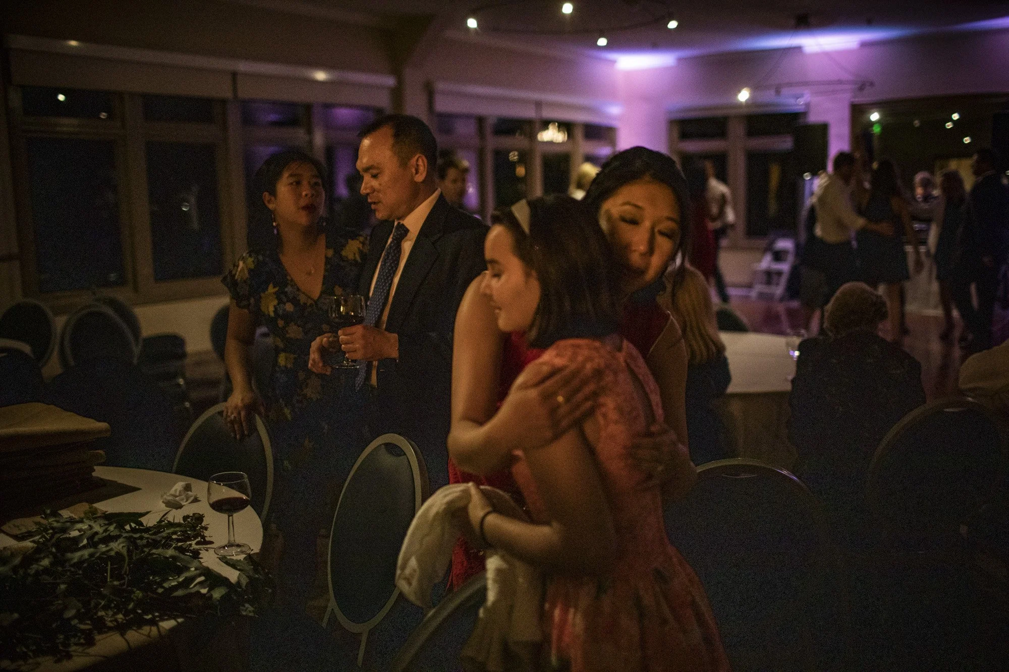 Wedding guests dancing together beneath colorful reception lights.