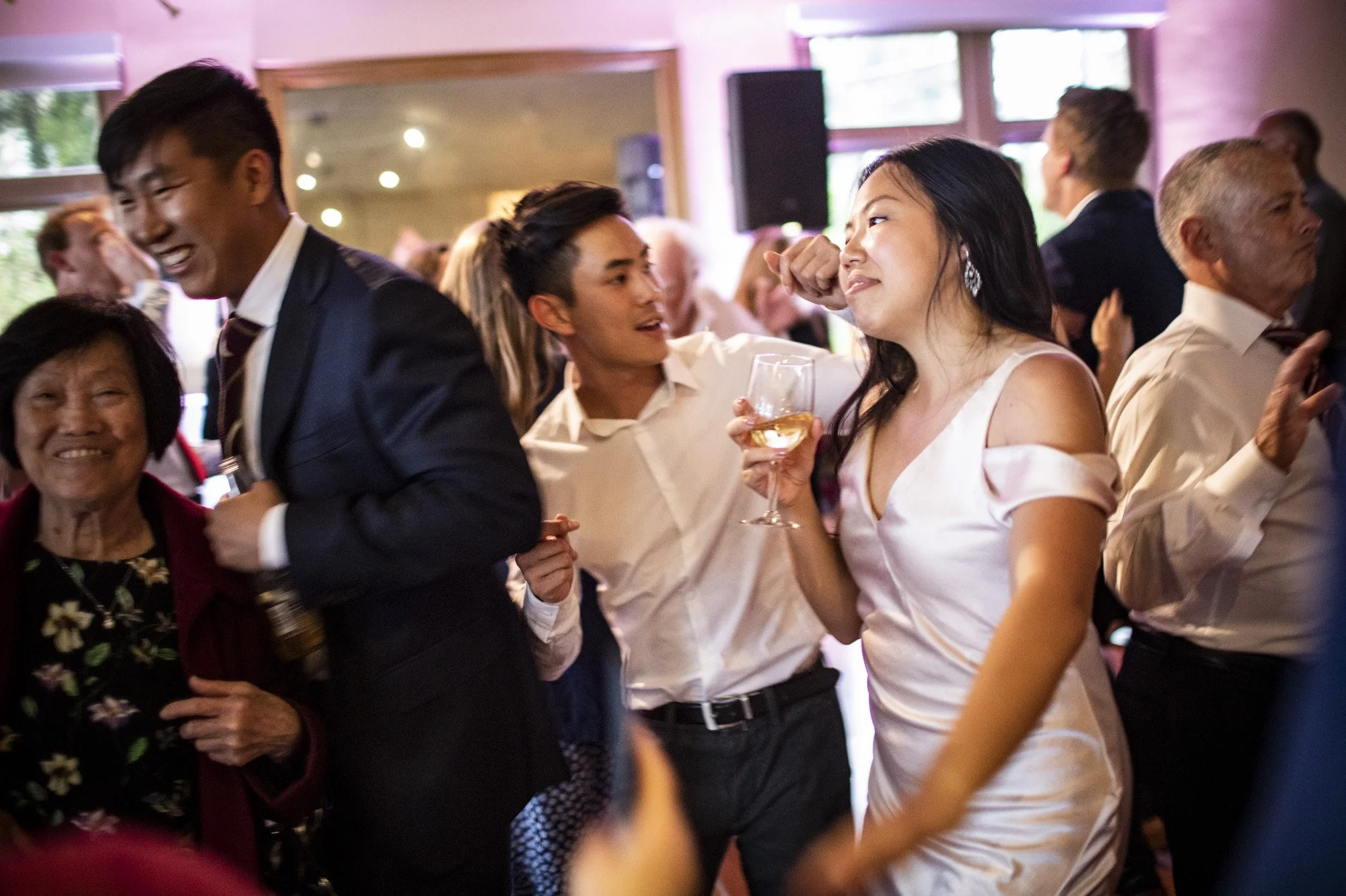 Couples dancing and laughing with guests at reception.