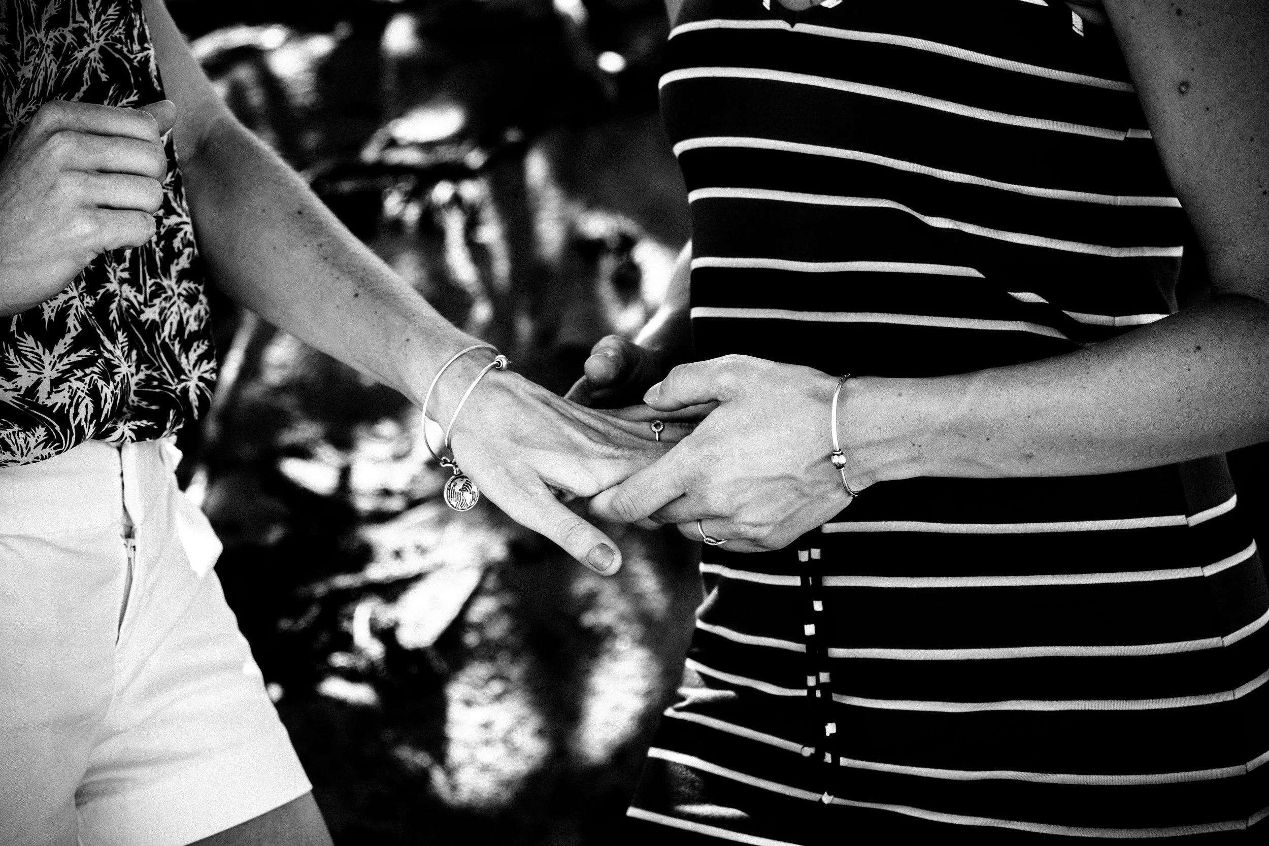 Close-up of a couple holding hands and showing an engagement ring.