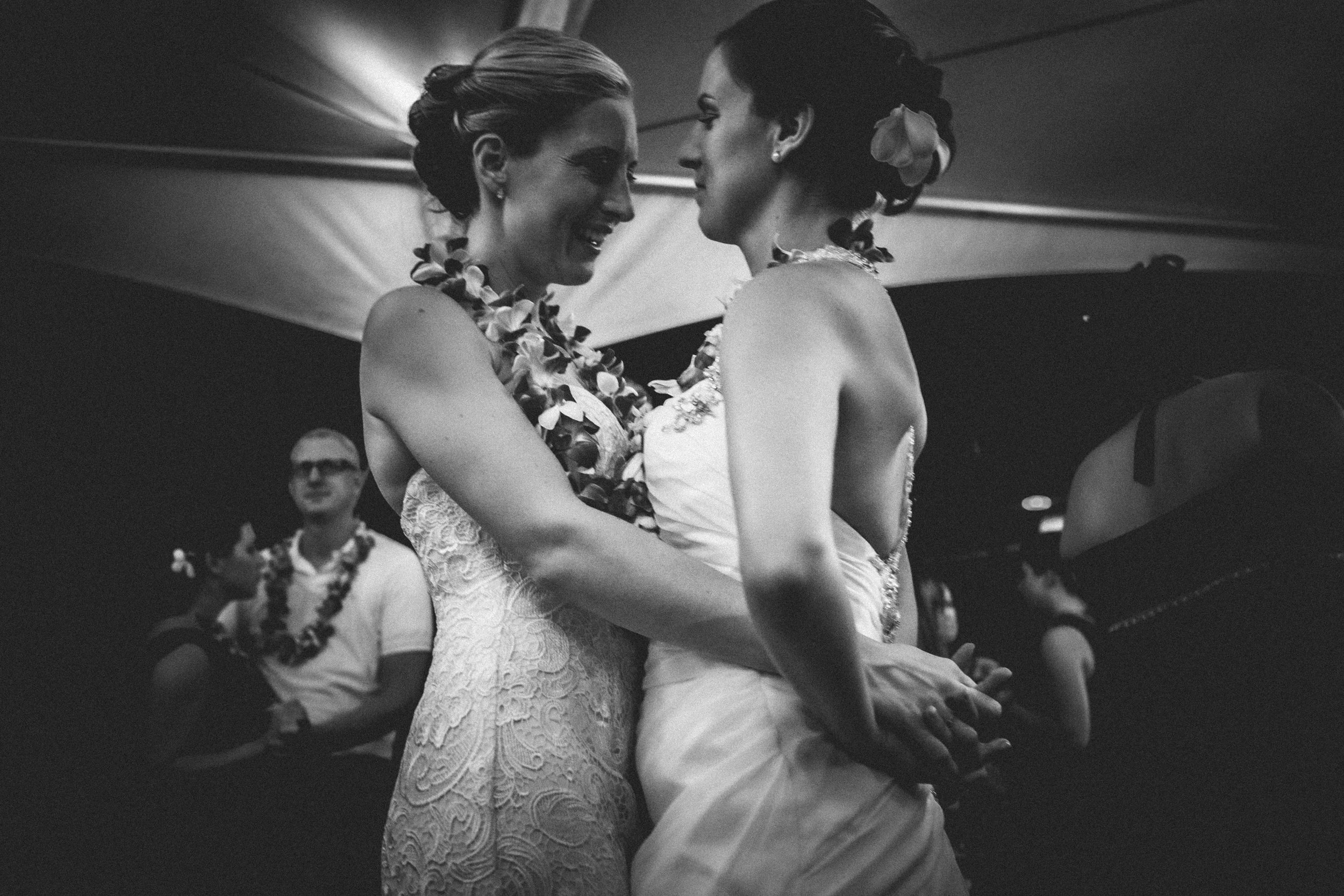 Two brides holding each other during an emotional wedding moment in black and white.
