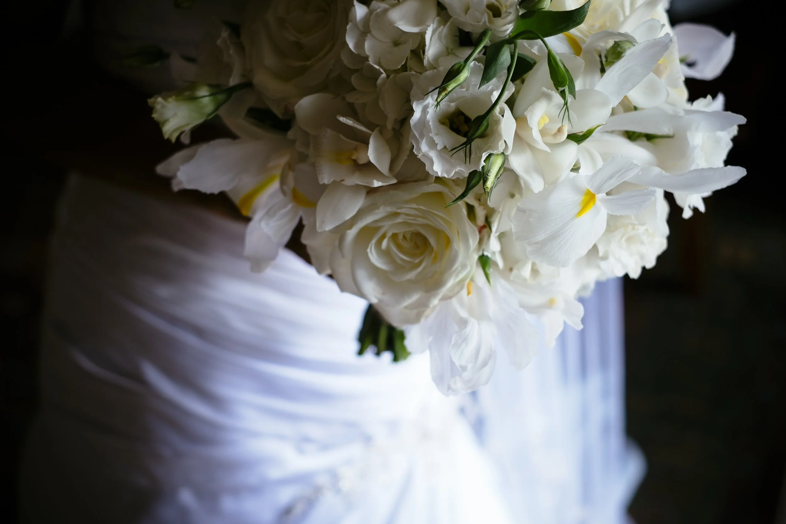 White bridal bouquet resting against a wedding dress.