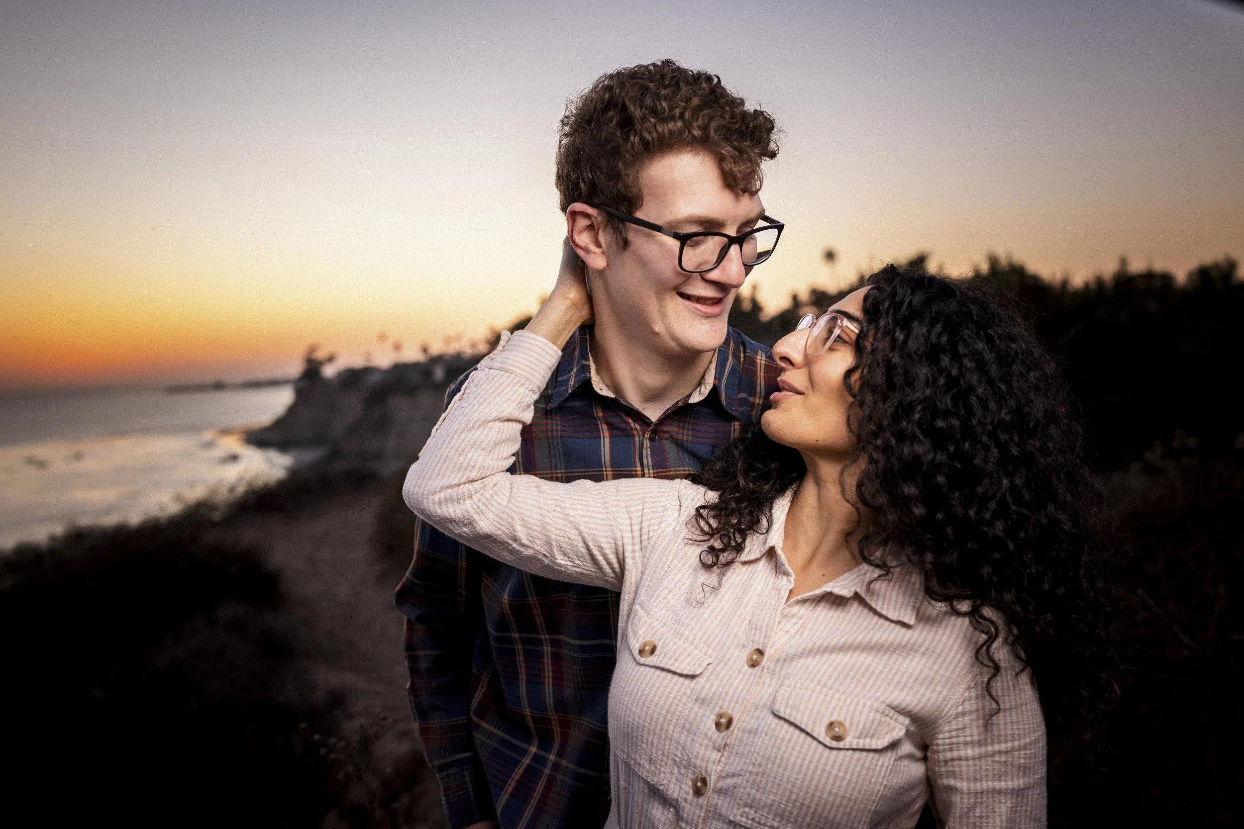 Newly engaged couple laughing together during sunset portraits.