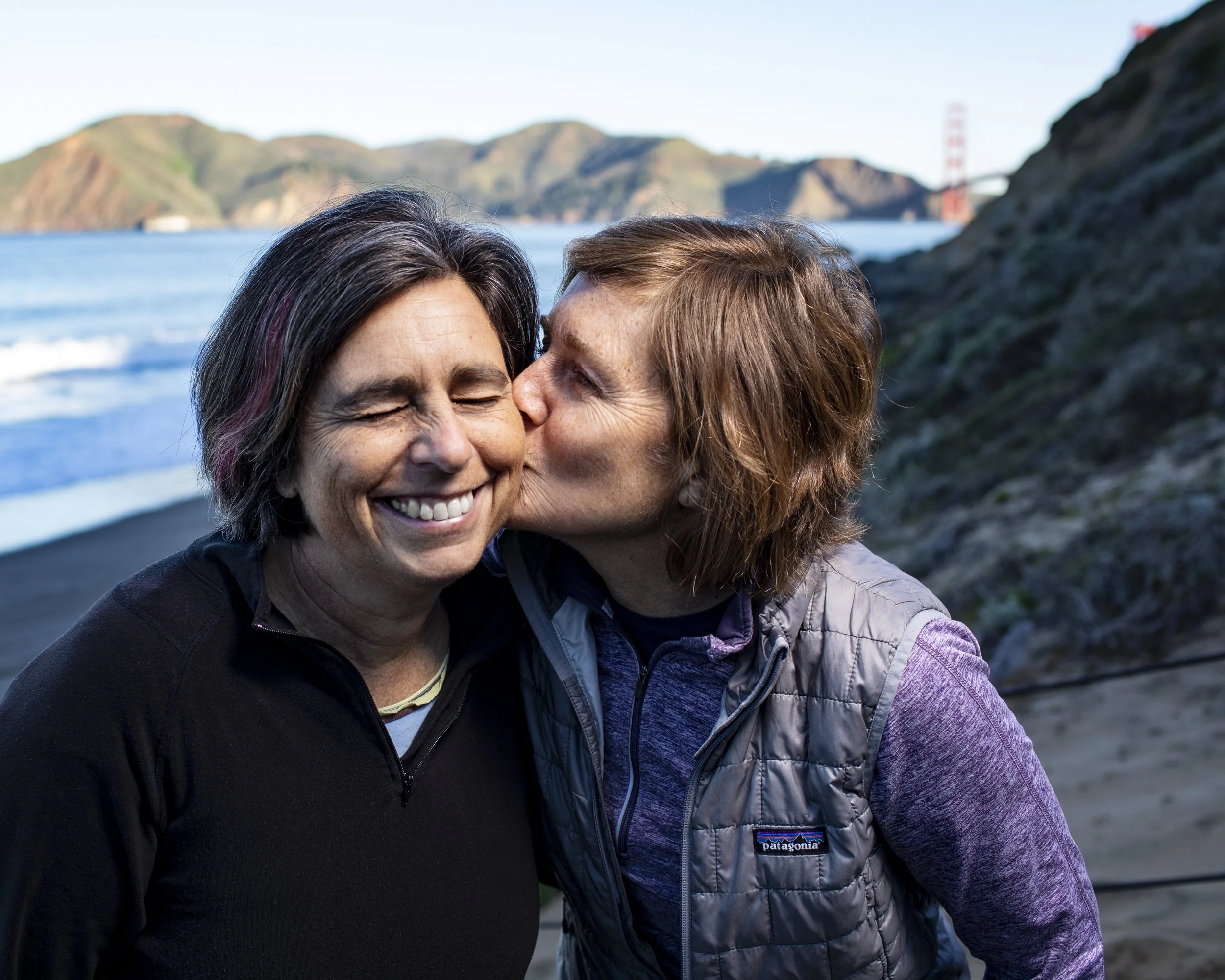 Couple kissing beside the Golden Gate Bridge during an outdoor portrait session.