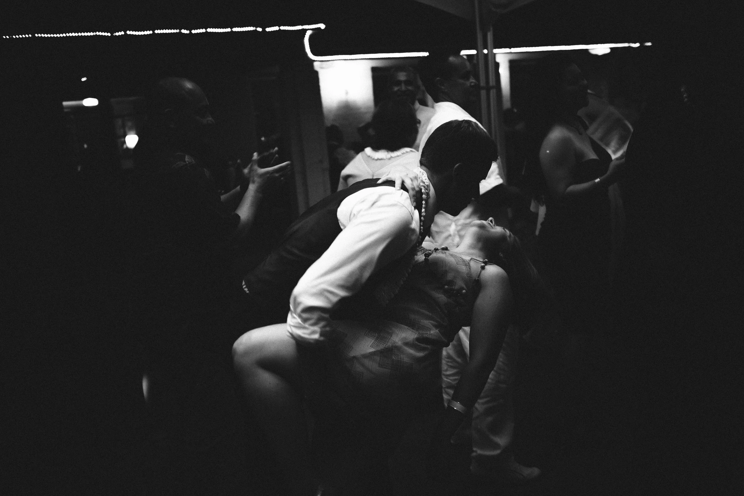 Couple kissing on a dark wedding dance floor in black and white.
