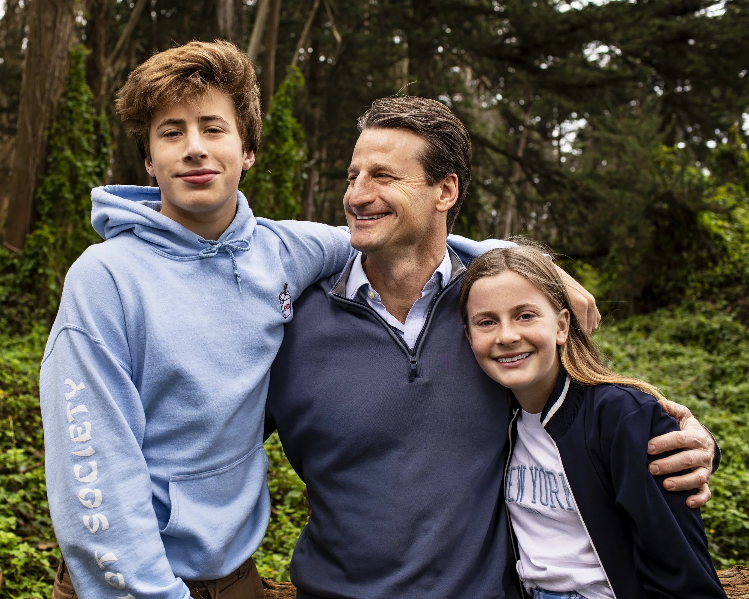 Father standing with two children during an outdoor family portrait.