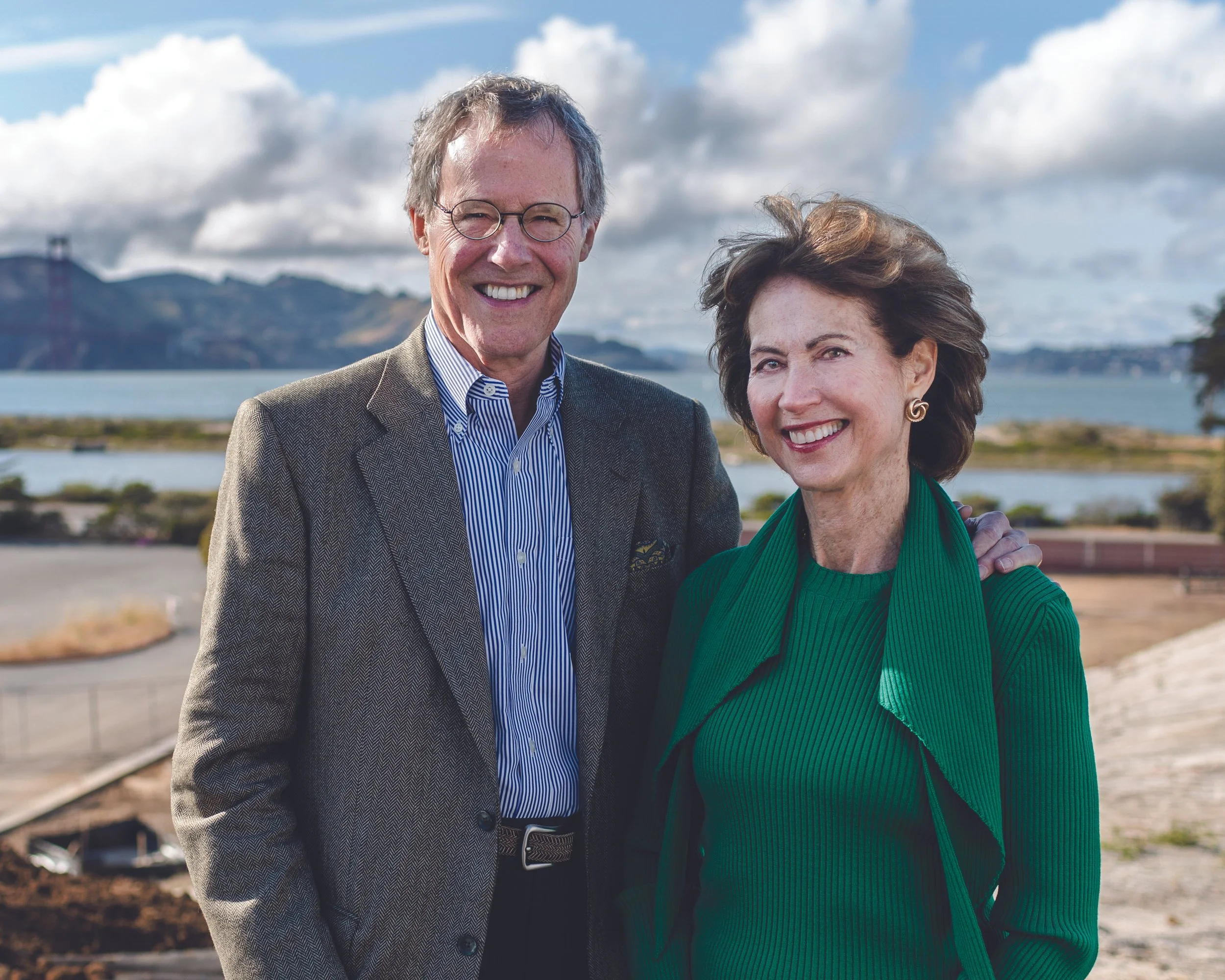 Two professionals smiling together in a coastal environmental portrait.