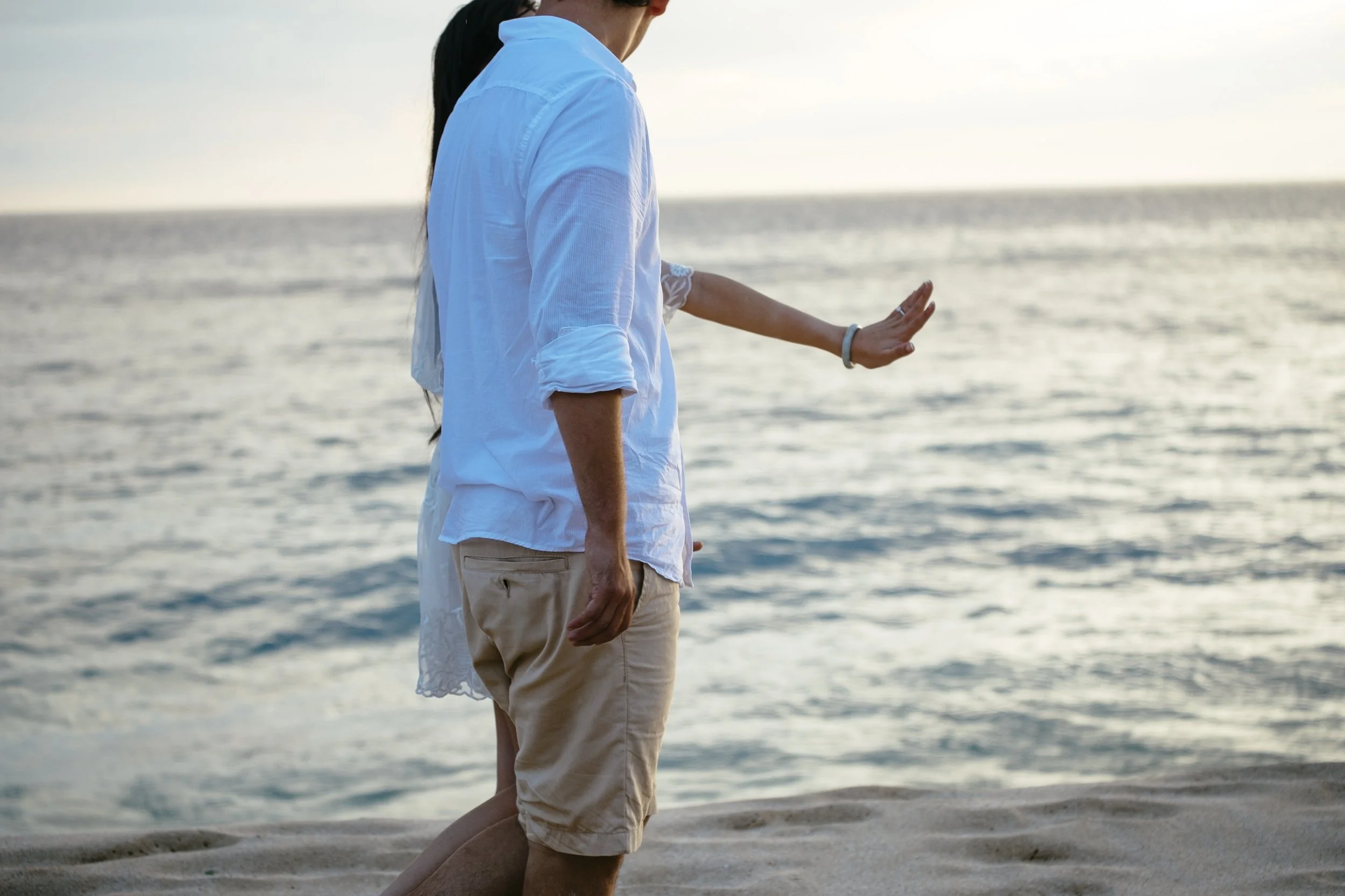 Couple admiring an engagement ring while standing together on the beach.