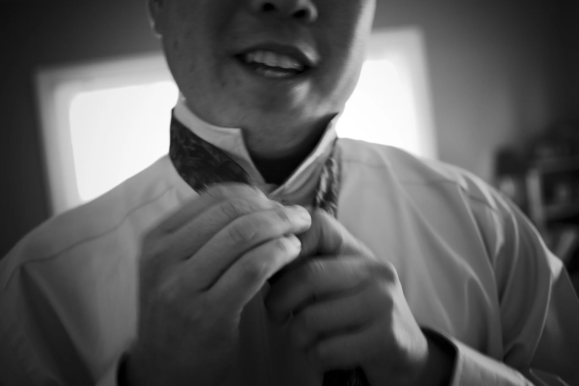 Close-up of a groom adjusting his tie before the wedding.
