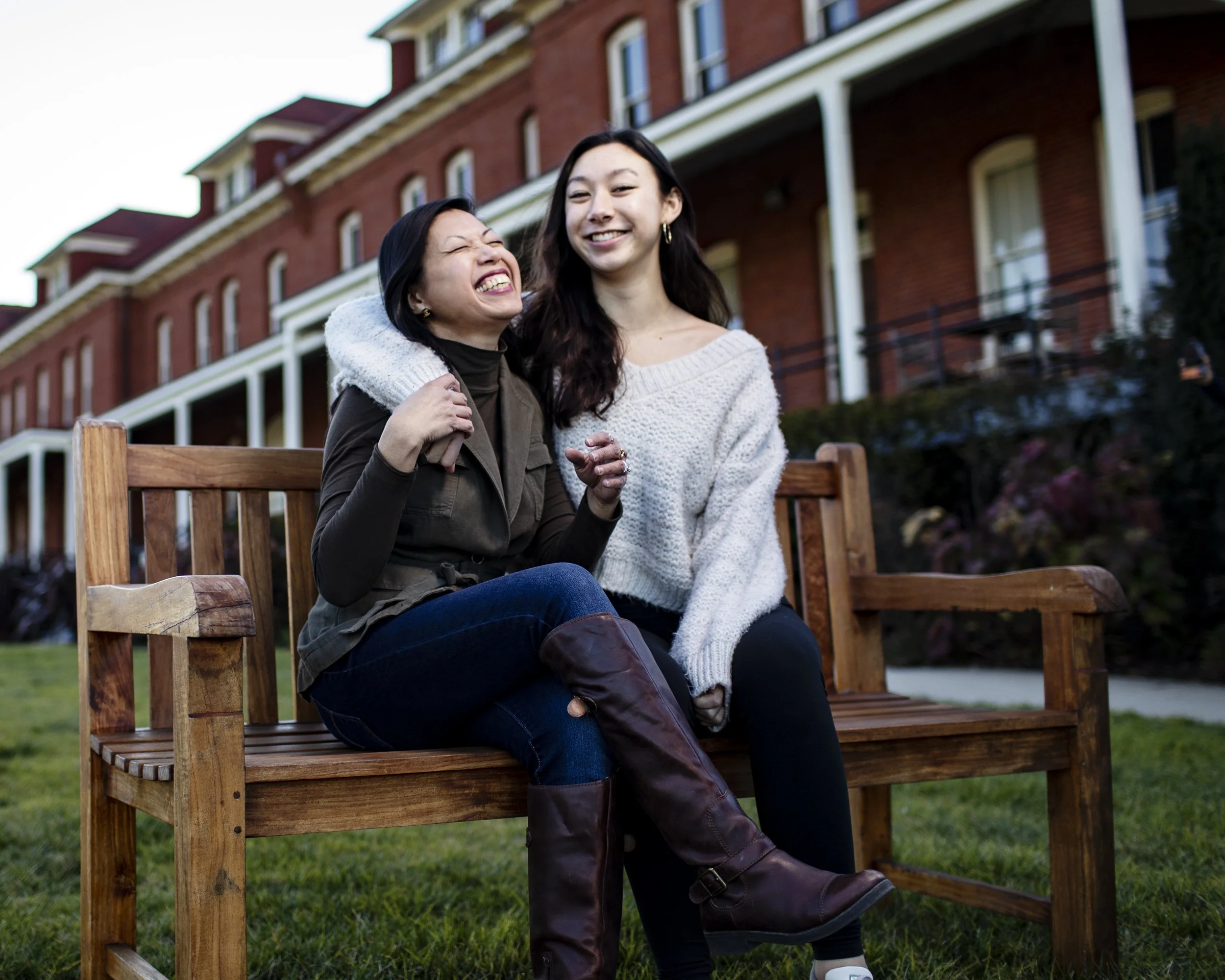 Mother and daughter laughing together while seated outside a historic building.