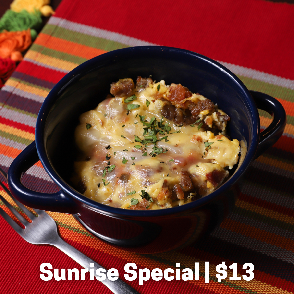 An egg scramble with fried tater tots, bacon, sausage, and pepper jack cheese in a bowl.