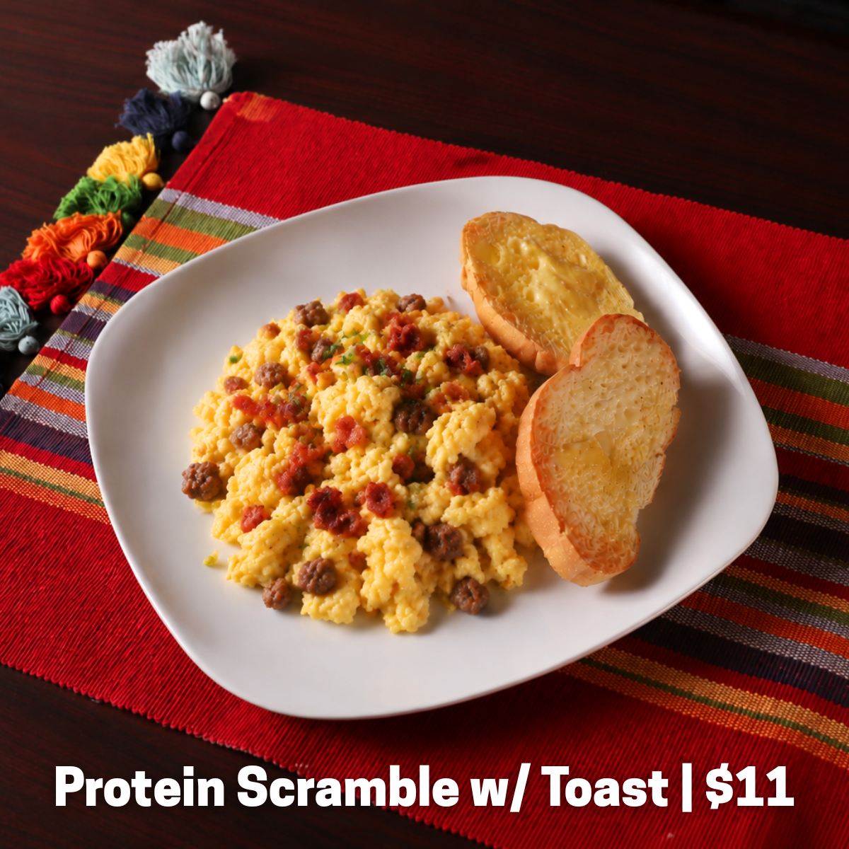 Scrambled eggs with sausage and bacon, served with toast.