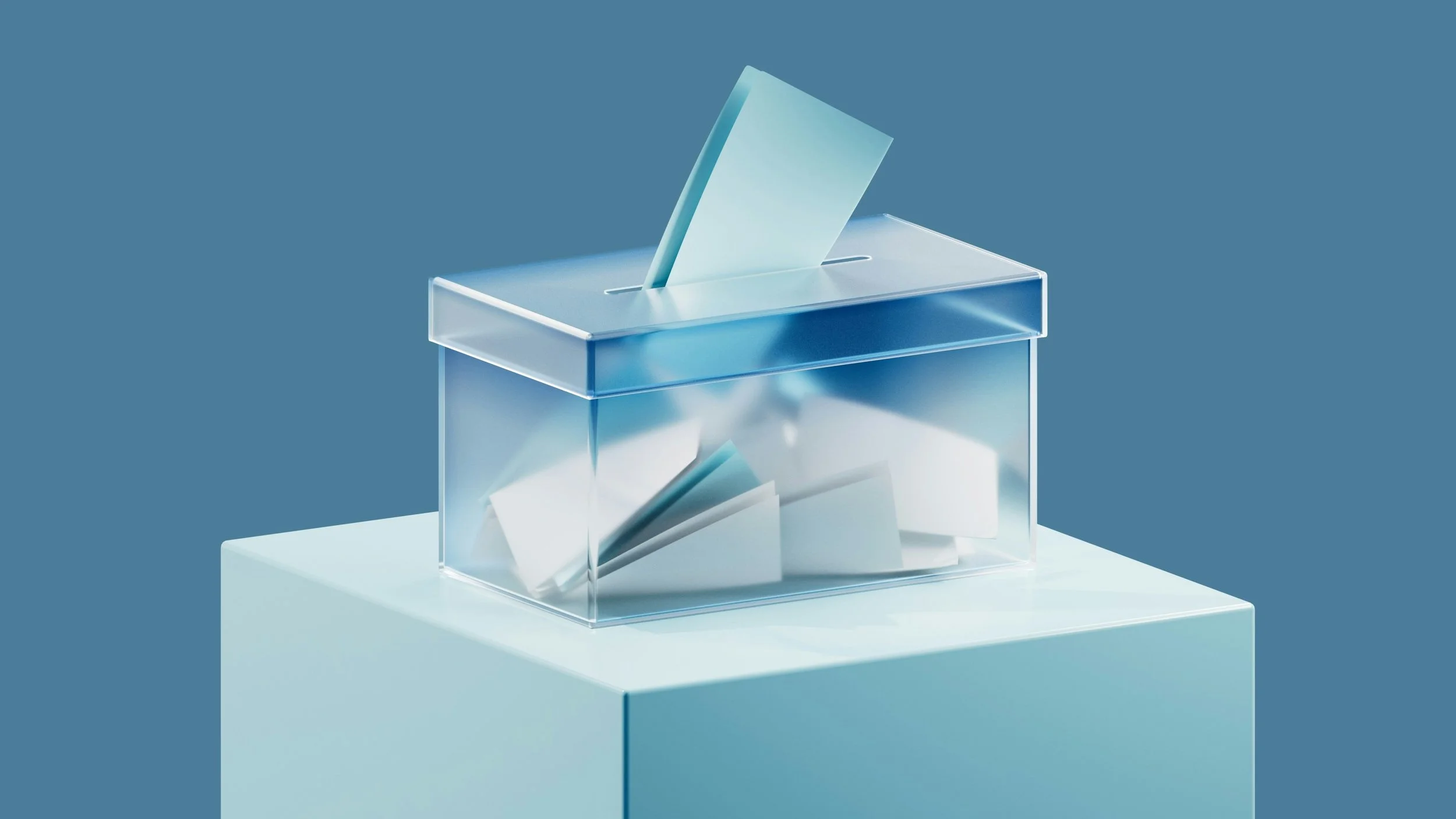 A clear acrylic ballot box with a slot on top, placed on a white surface against a blue background, with a ballot partially inserted.