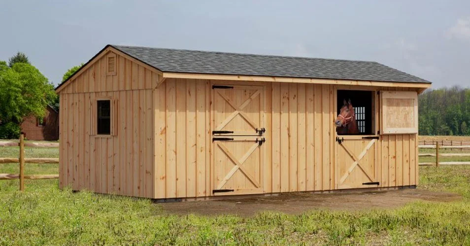 Exterior of a wooden barn, showcasing animals and spacious workspaces.