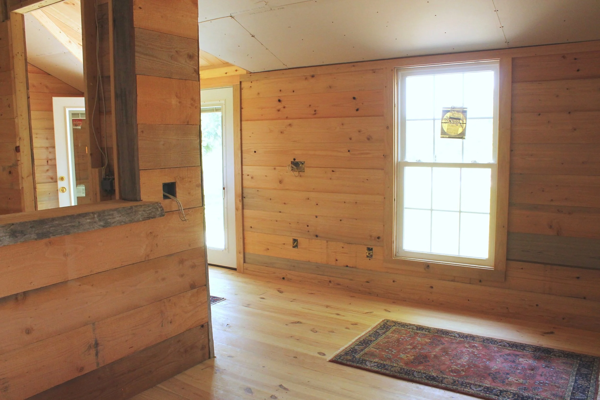 Cozy interior of a tiny home made of reclaimed wood, featuring a compact kitchen and living area.