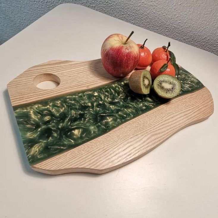 Wooden serving tray with green epoxy resin with fresh fruit laying on top.